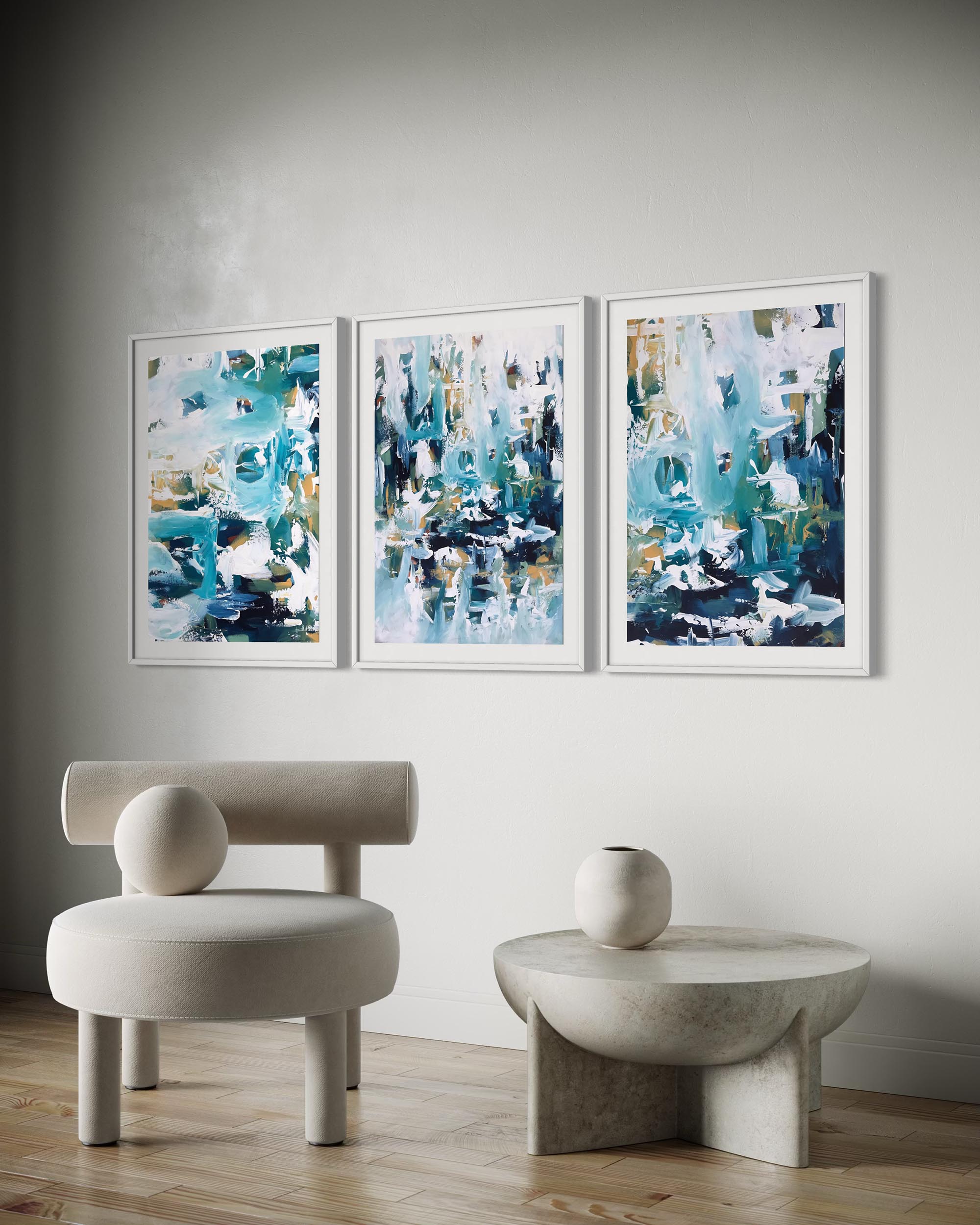 Three abstract paintings on a wall above a modern chair and table.