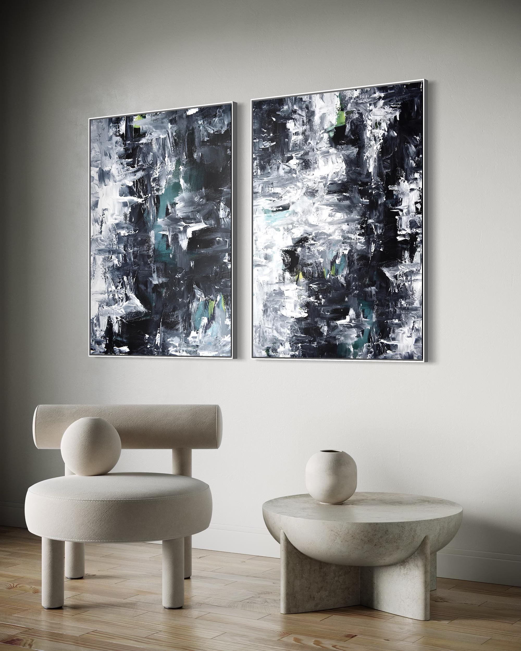 Two abstract paintings on a wall above a modern chair and table.