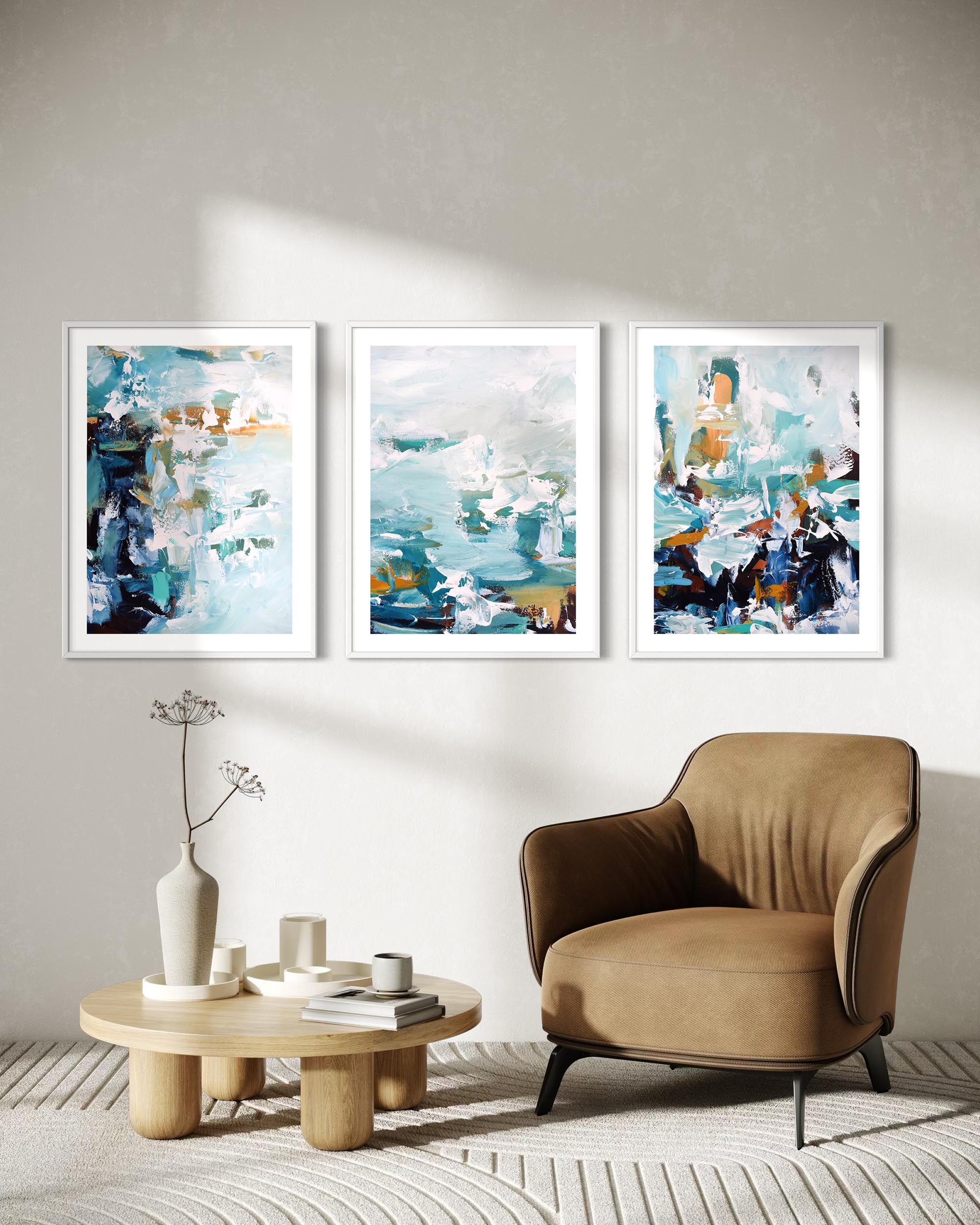 Three abstract paintings on a wall above a beige armchair and wooden coffee table.