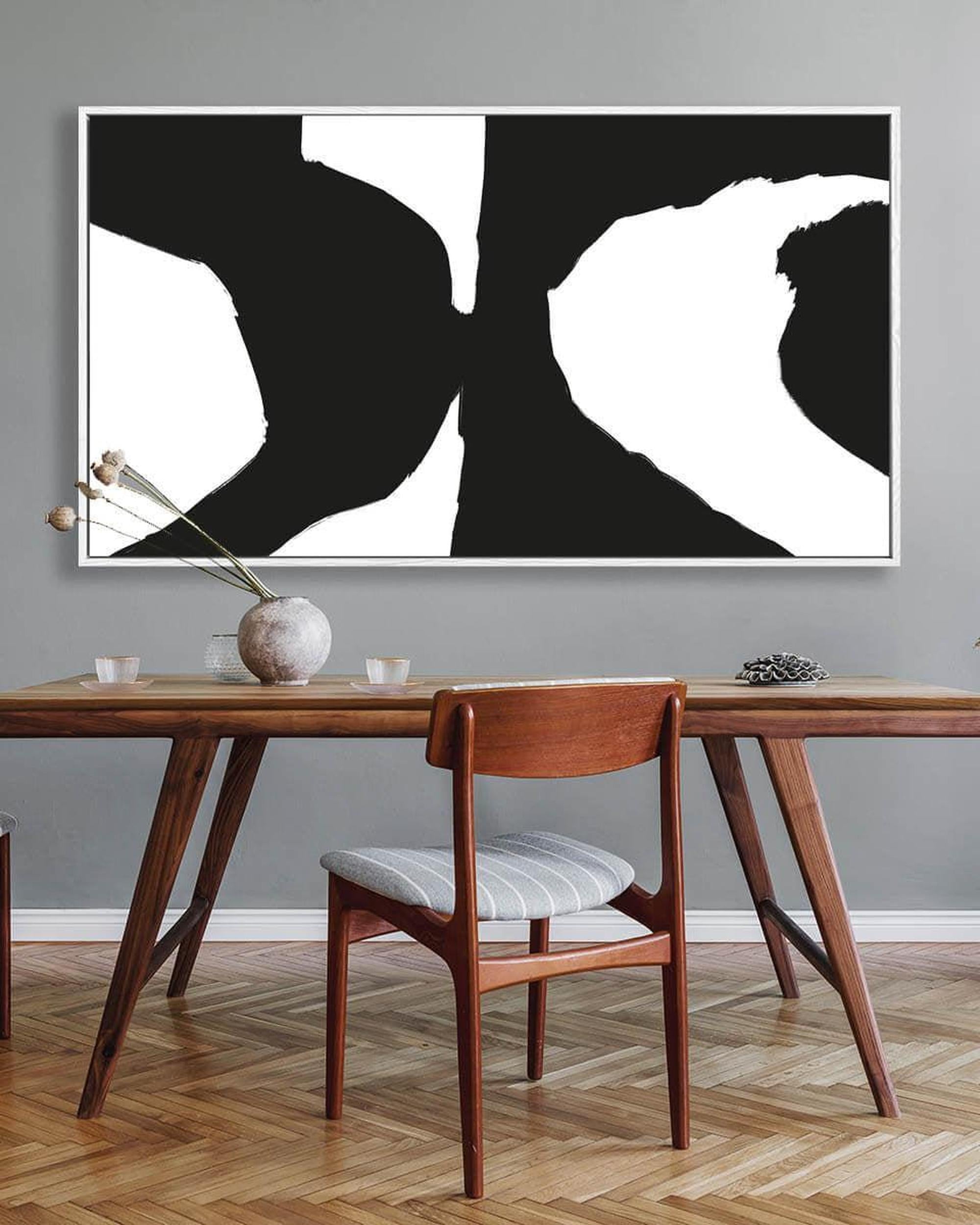 Dining room with a wooden table and chair, abstract black and white art on the wall.