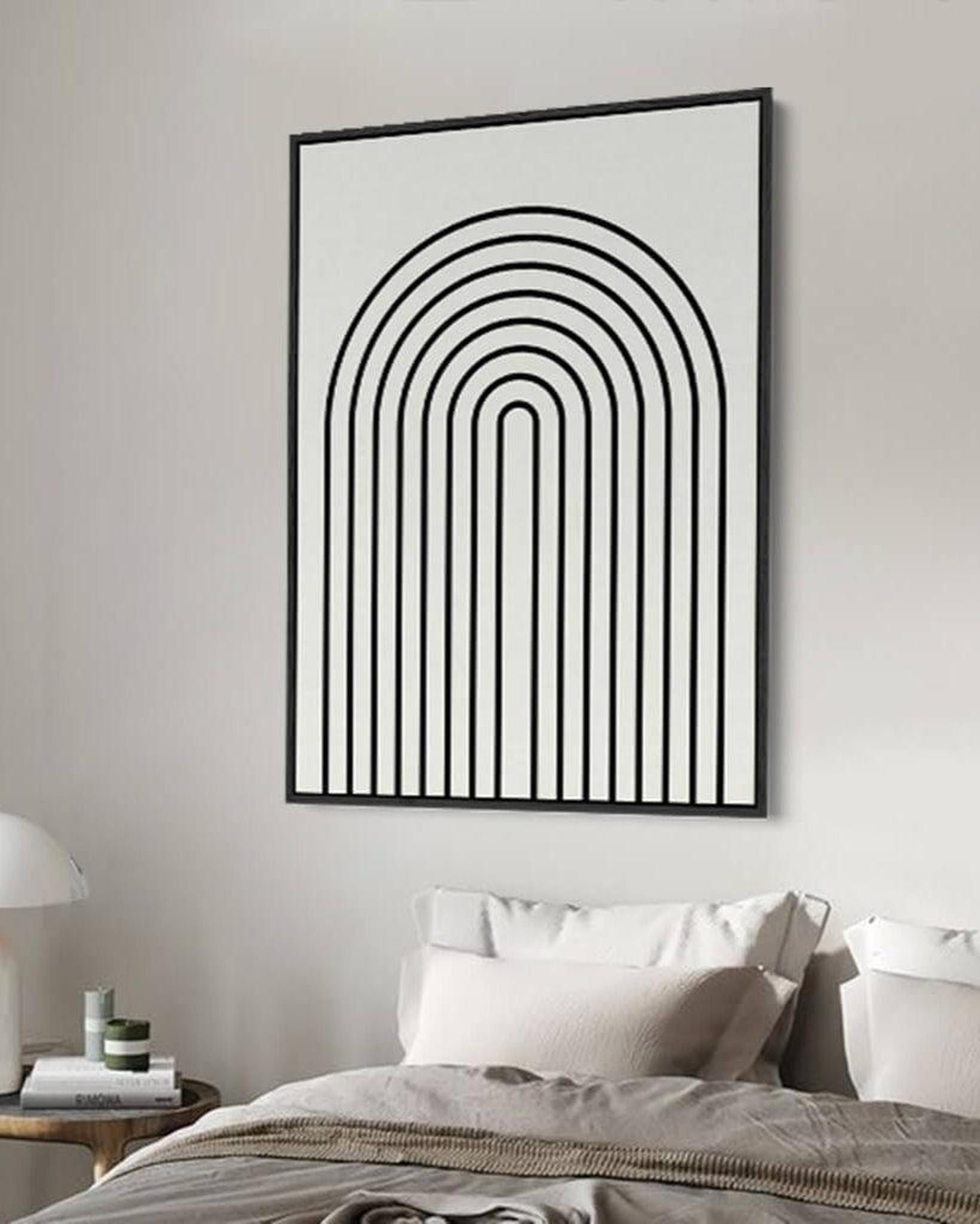 Framed abstract art with black lines on a white background in a bedroom setting.