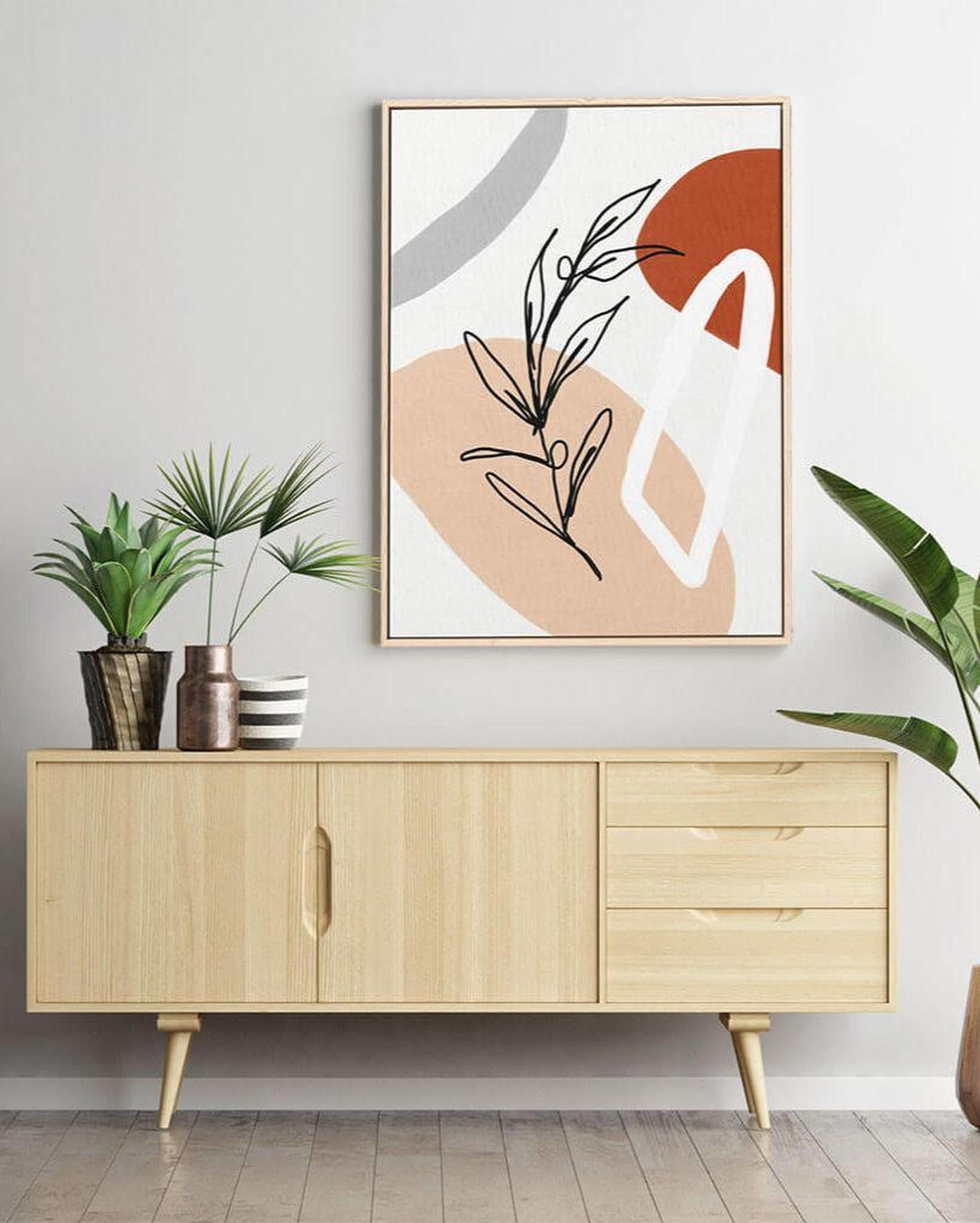 Wooden sideboard with abstract art and plants in a room.