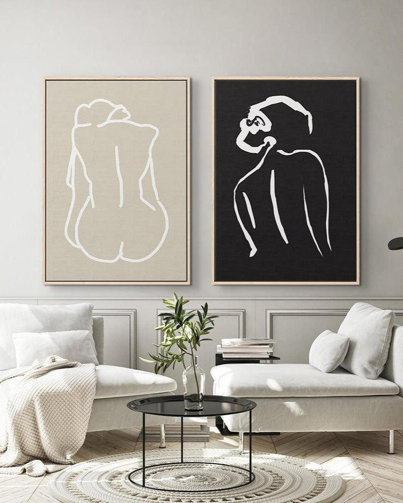 Two abstract art pieces of nude figures on a wall in a living room.