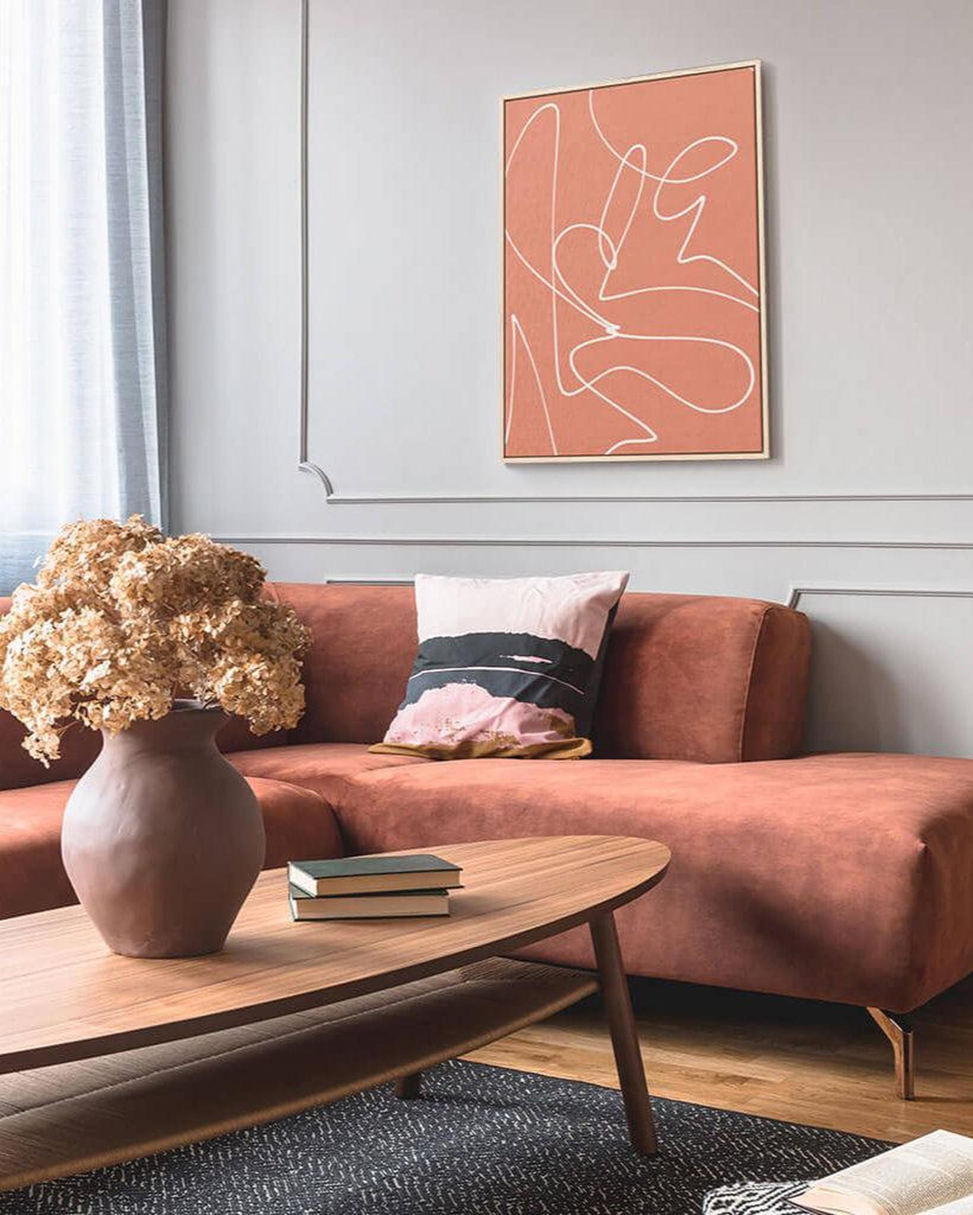 Living room with a brown sofa, wooden coffee table, and abstract art on the wall.