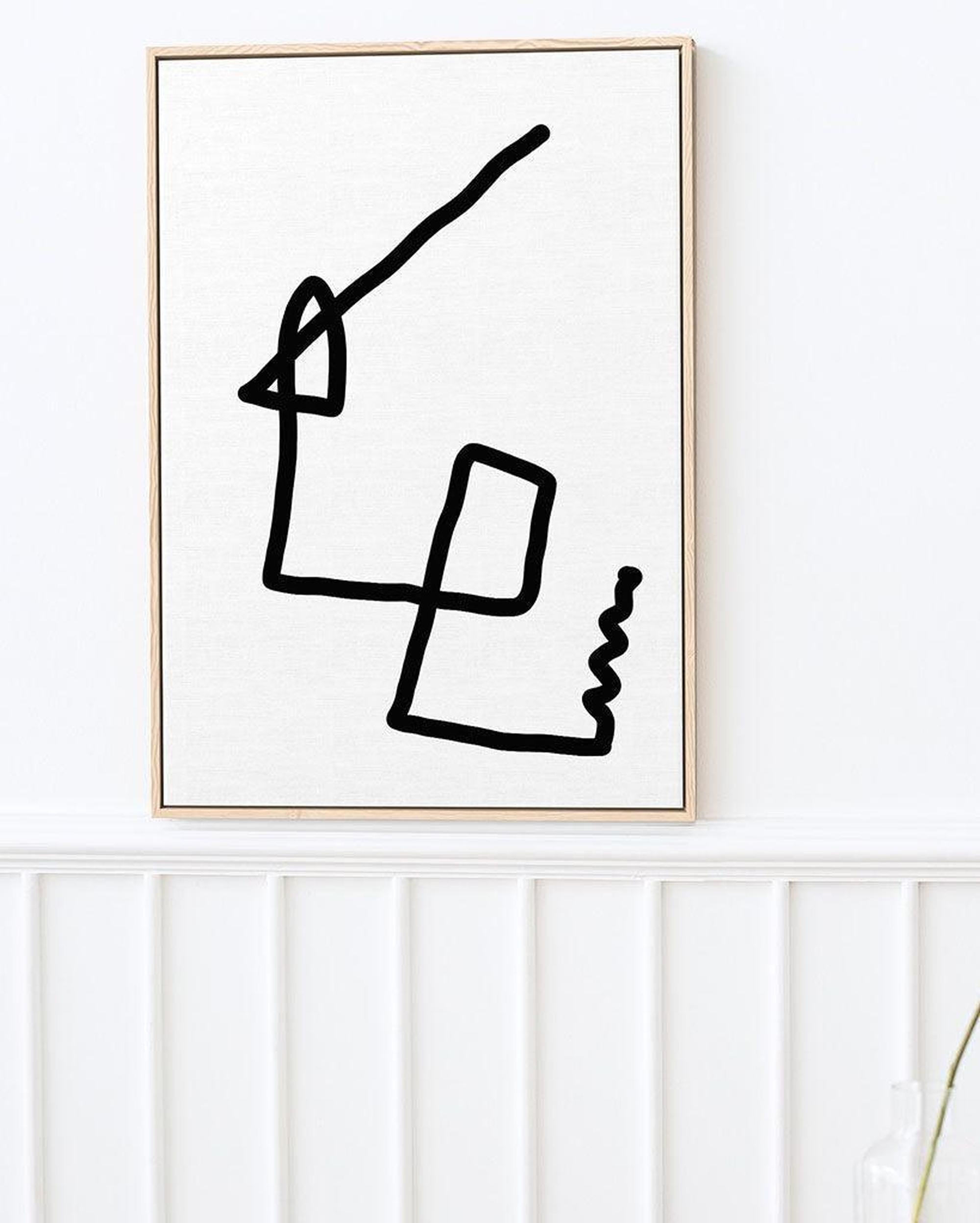 Abstract black line art in a gold frame on a white wall