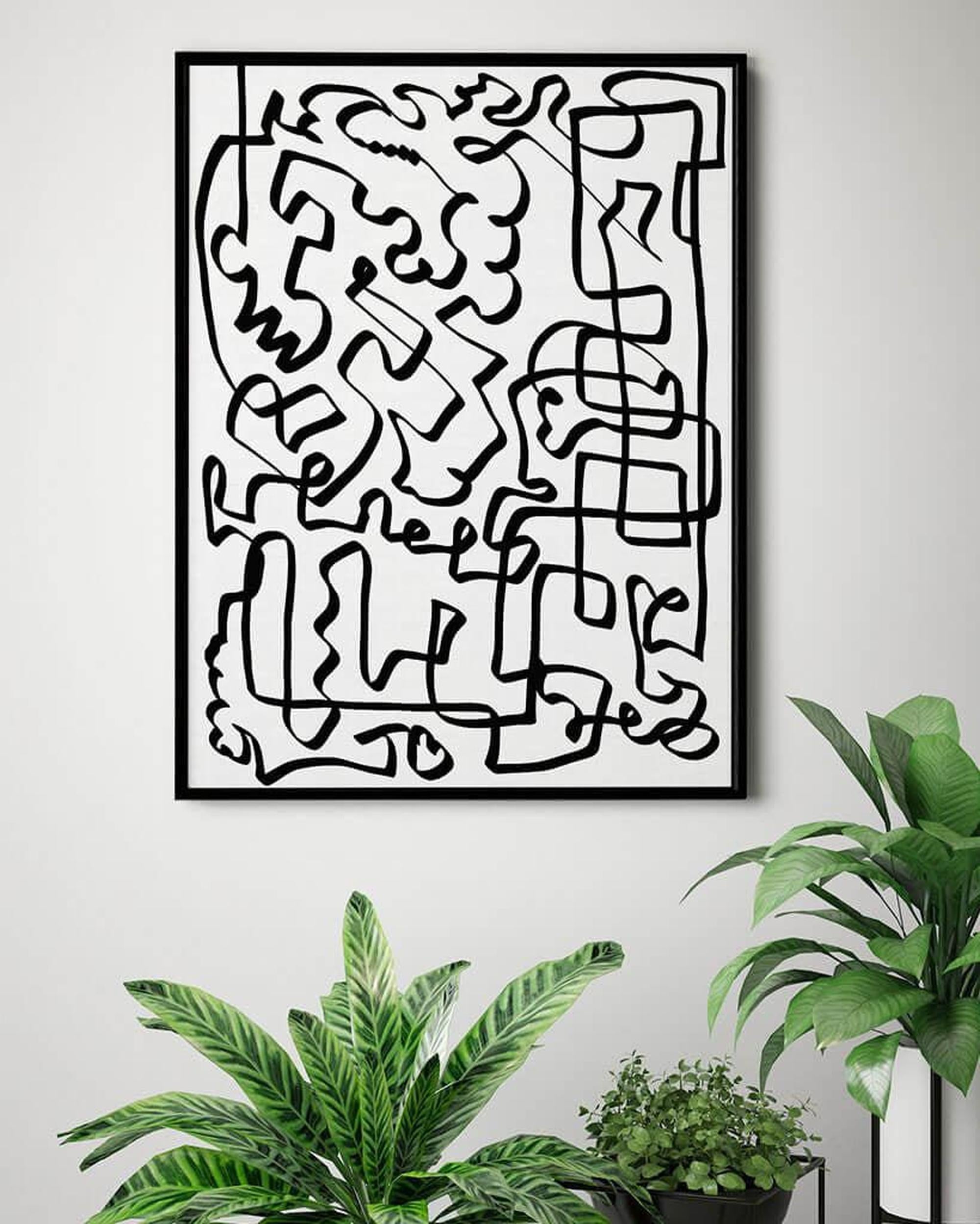 Abstract black line art on a white wall with plants below