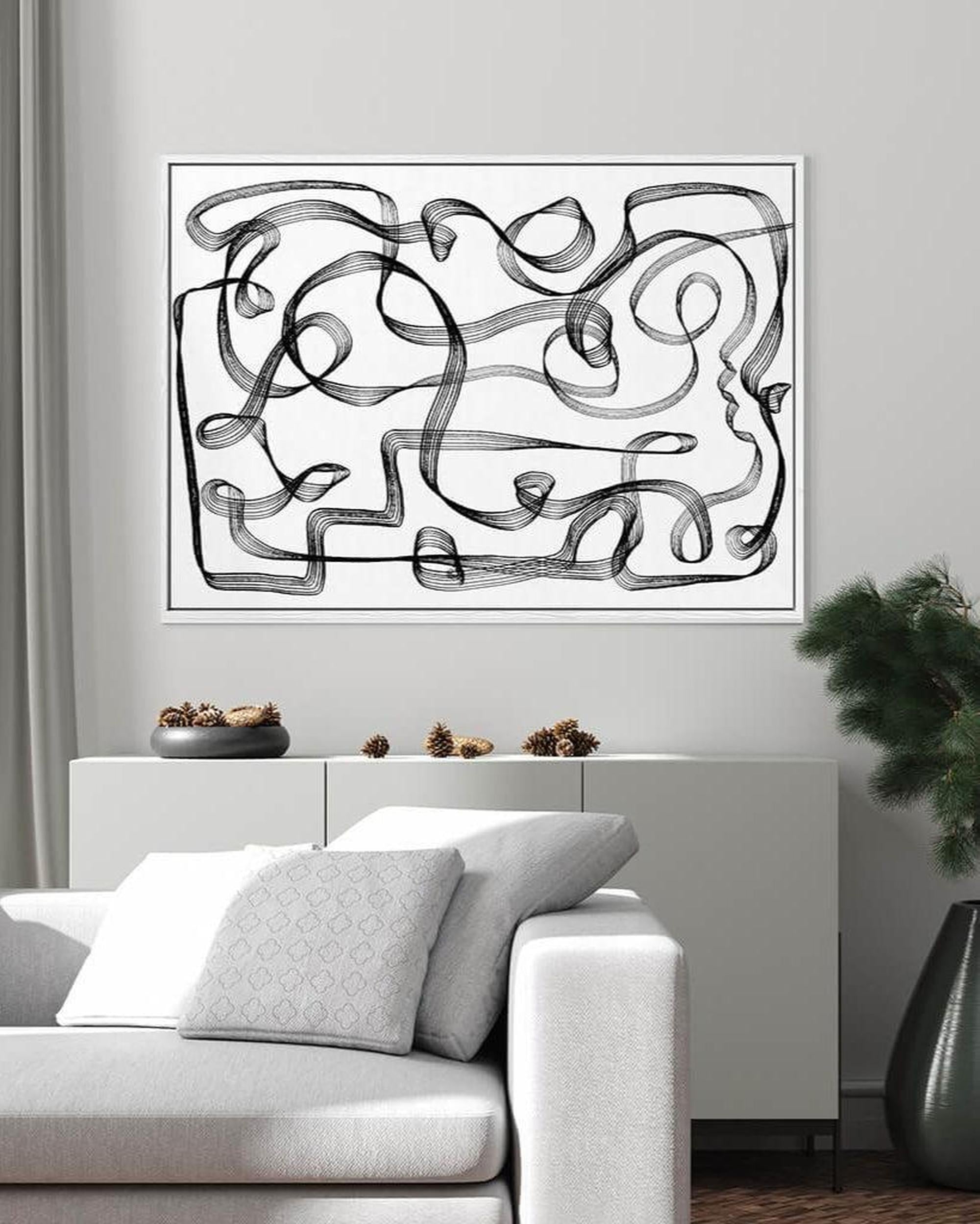 Abstract black and white artwork on a wall above a sofa in a living room.