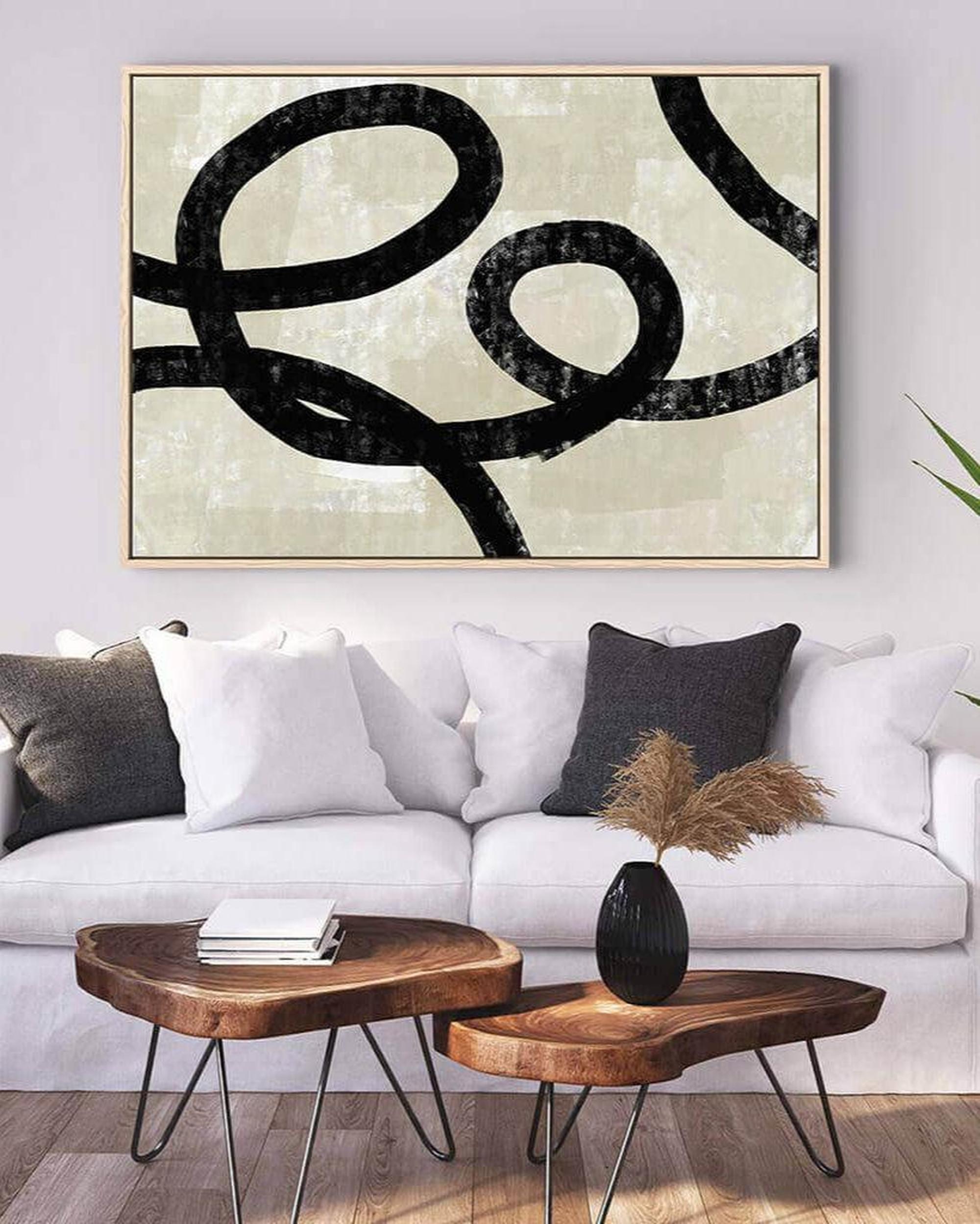Living room with a white sofa, wooden coffee table, and abstract art on the wall.