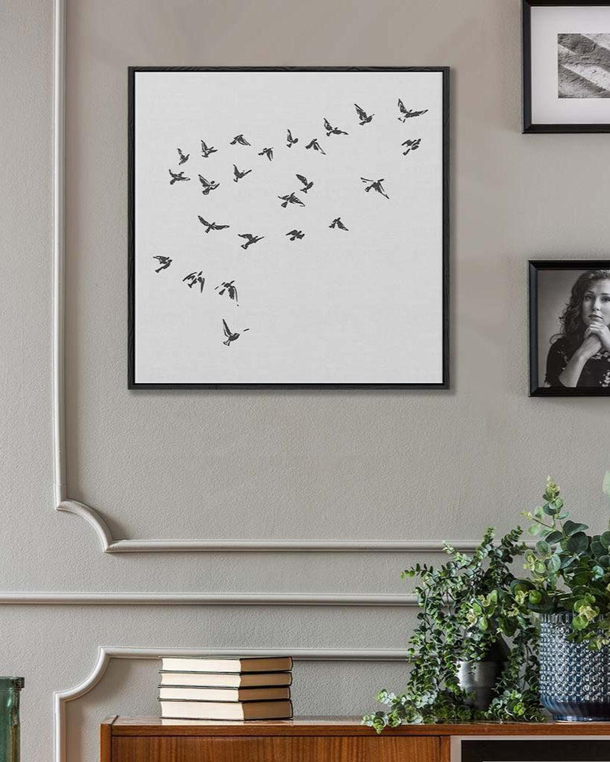 Framed artwork of birds on a white background in a room with decor elements.