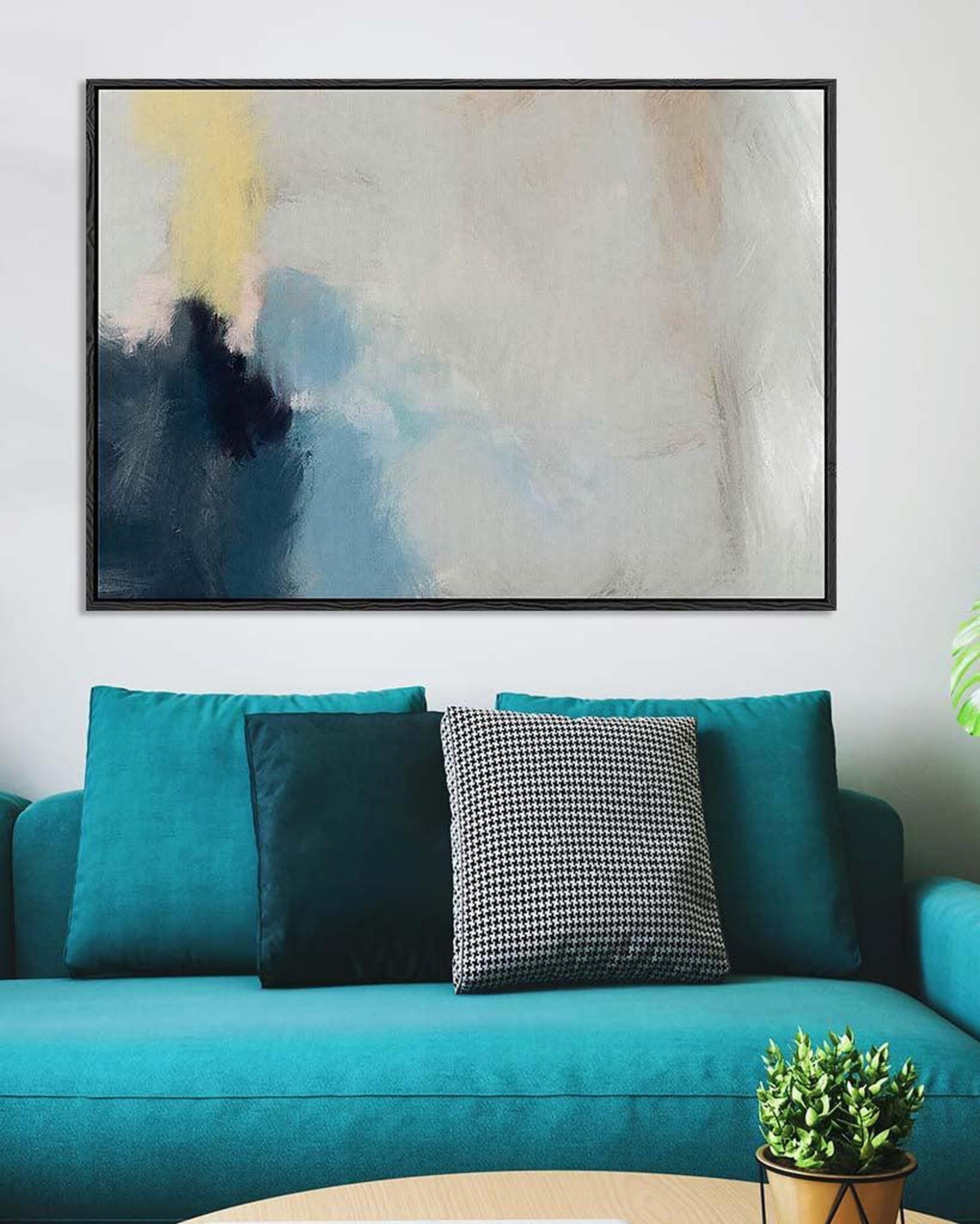 Teal sofa with decorative pillows and a plant, featuring an abstract painting above.