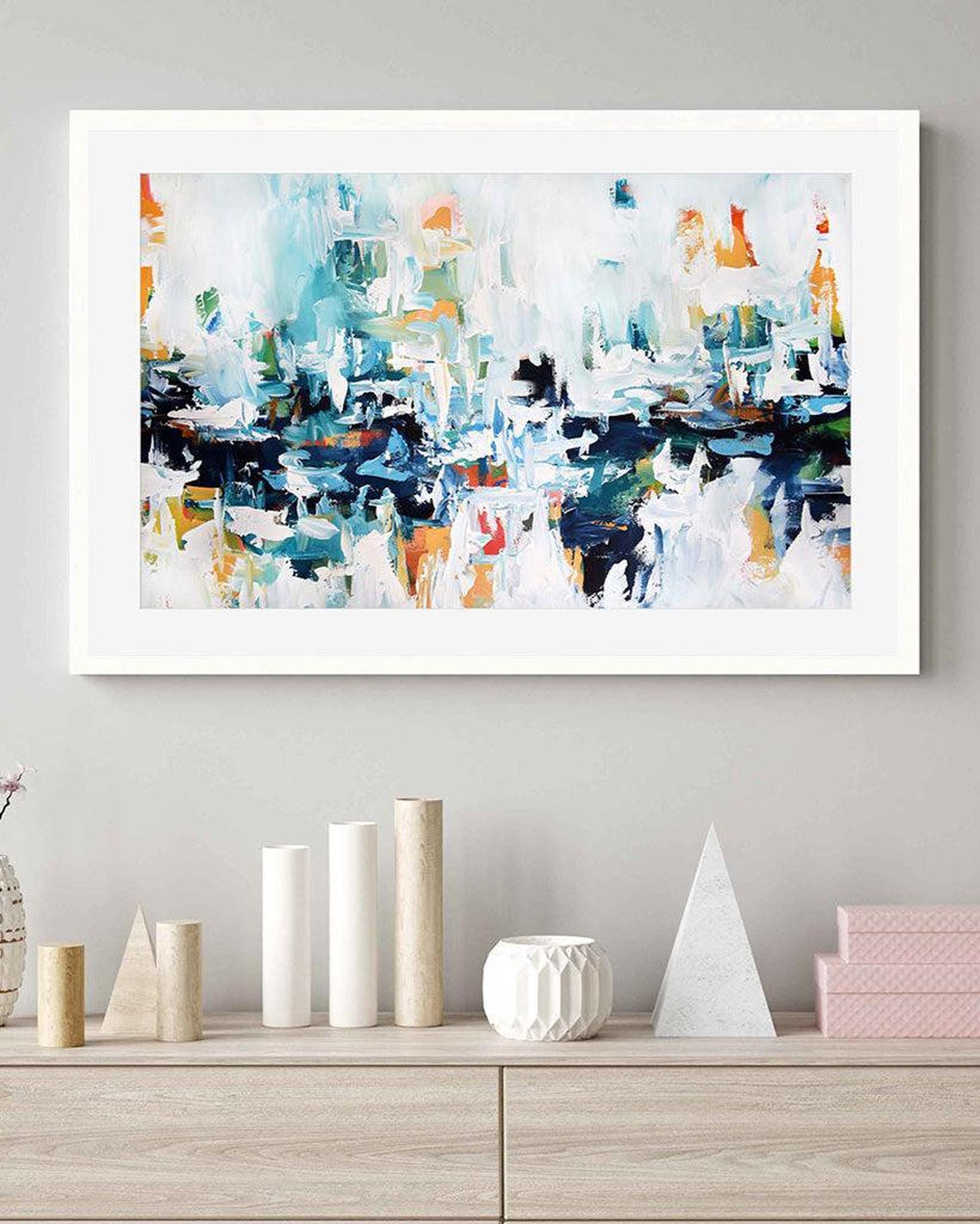 Framed abstract painting on a wall above a wooden shelf with decorative items.