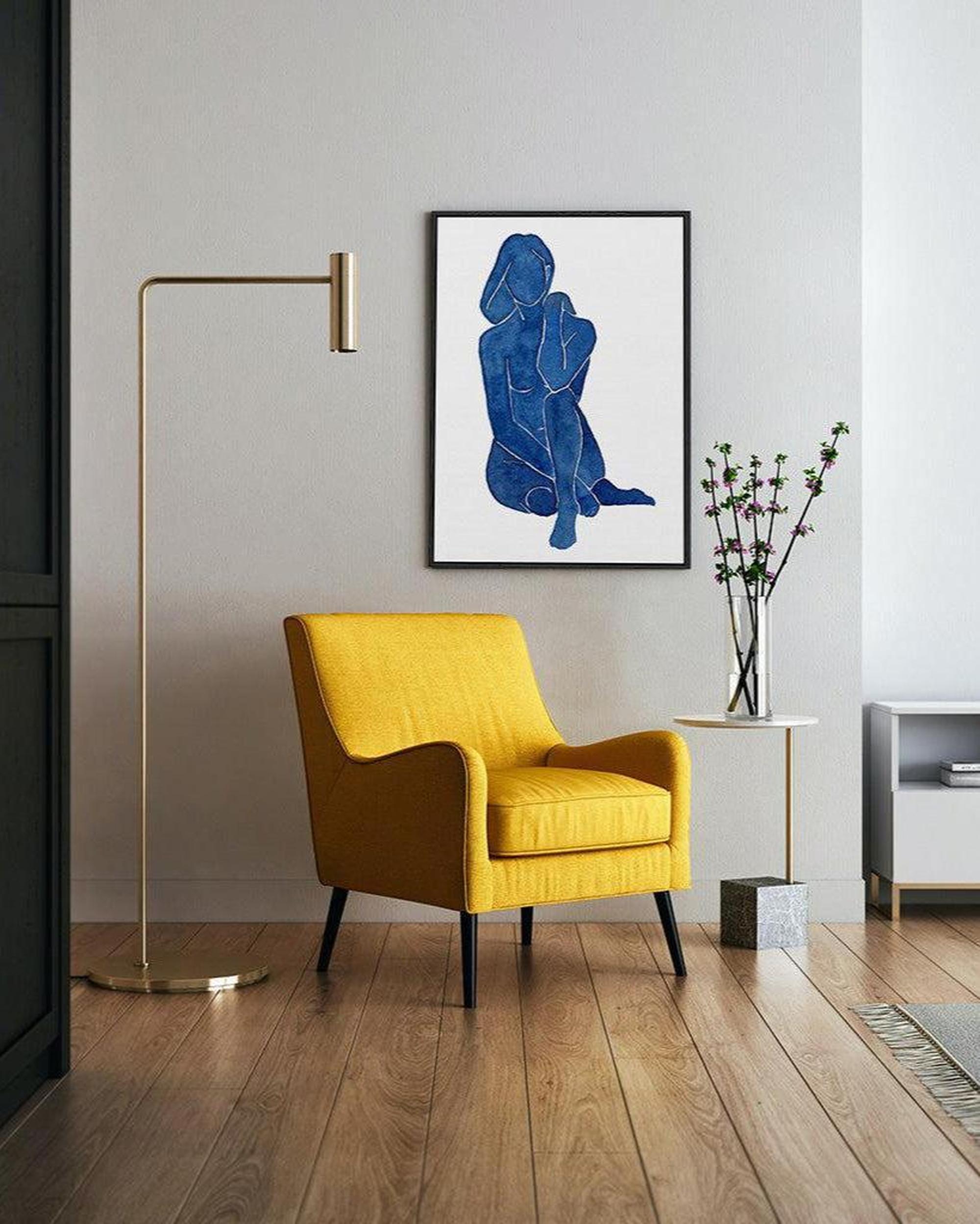 Yellow armchair in a modern living room with a blue abstract painting on the wall.