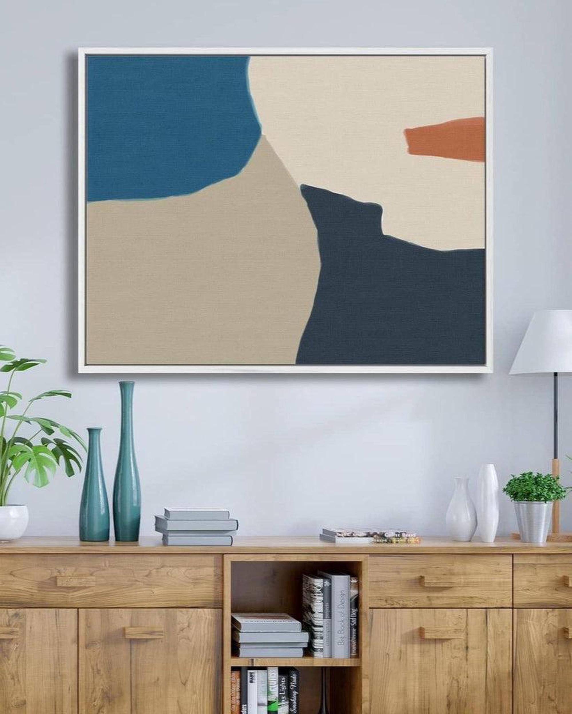 Abstract art piece on a wall above a wooden cabinet with decorative items.