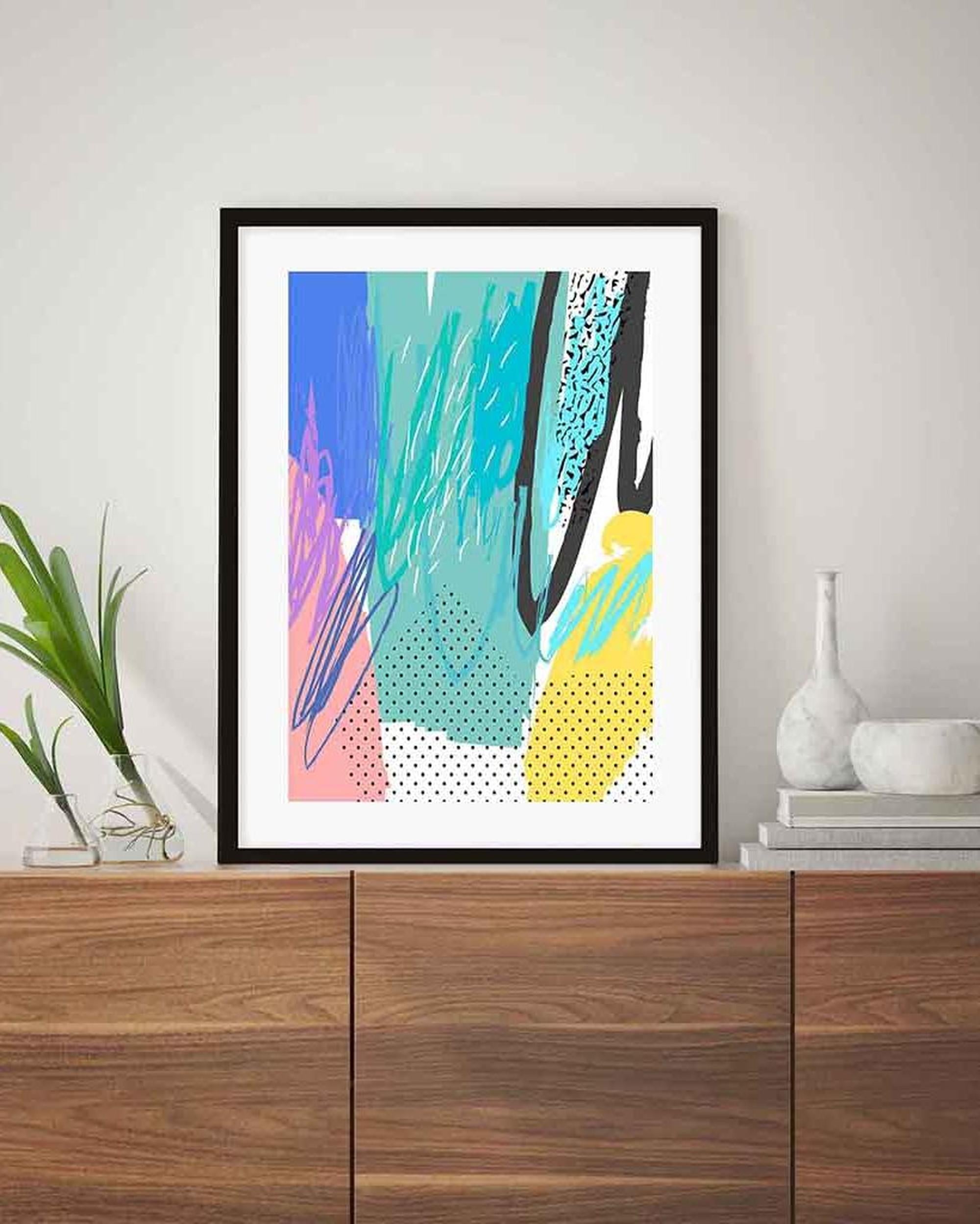Framed abstract art print on a wooden cabinet with decorative items.