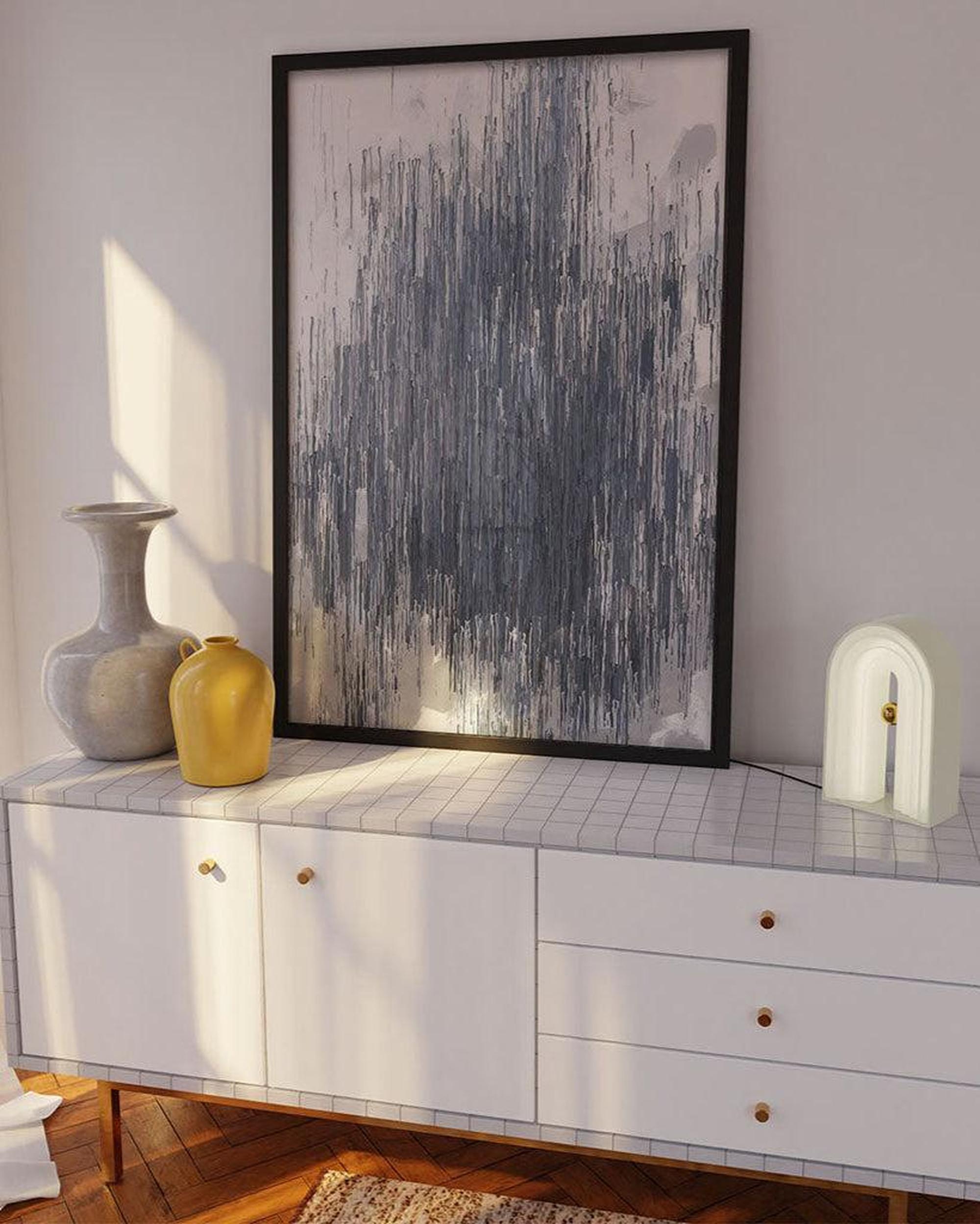 White sideboard with decorative items and abstract art on a wall