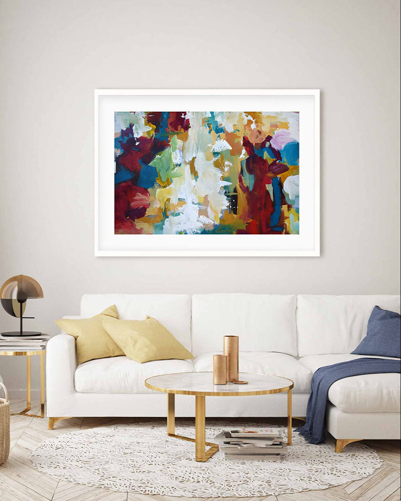 Colorful abstract painting on a wall above a white sofa in a living room.