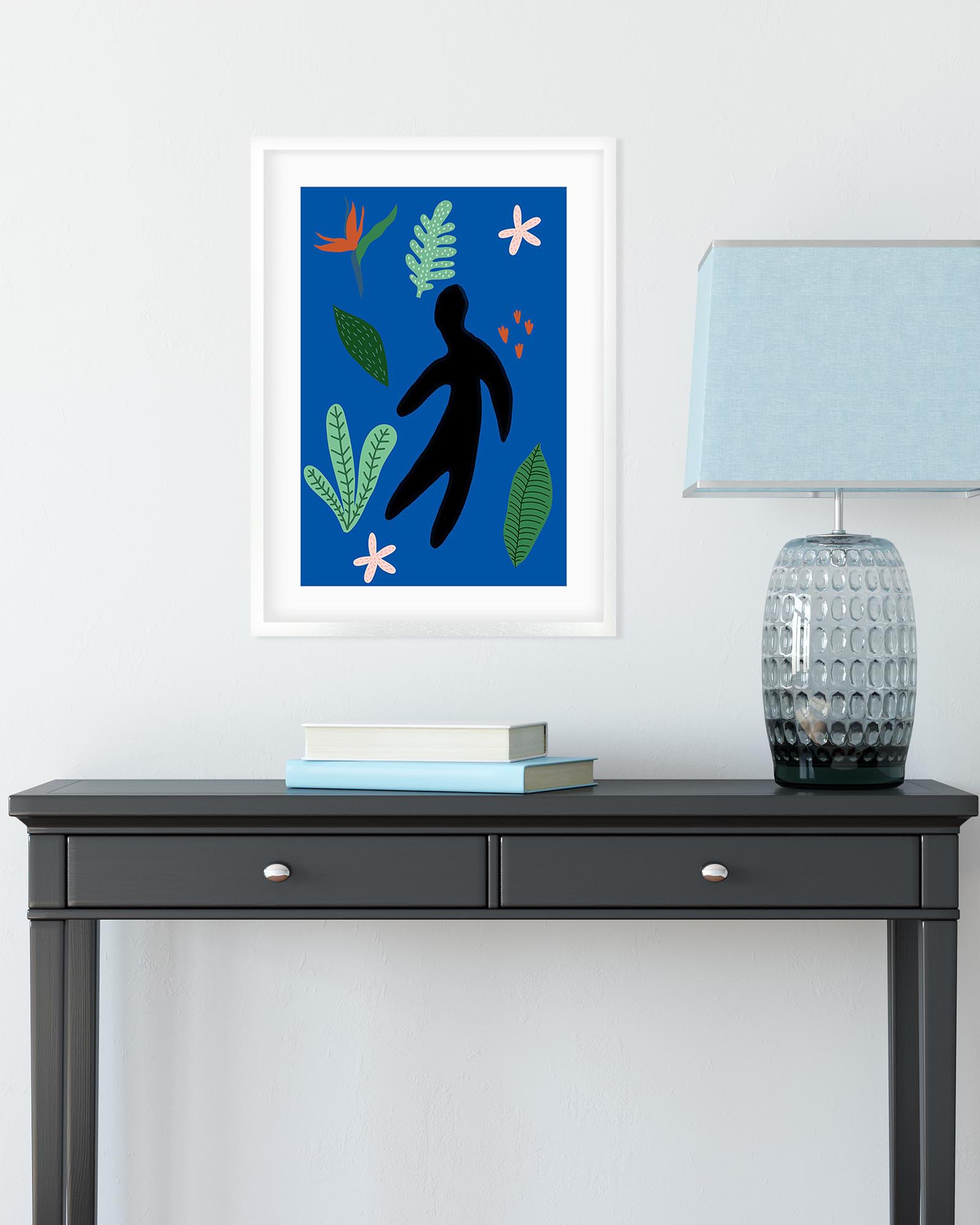 Framed artwork with a silhouette and colorful leaves on a wall above a black console table.