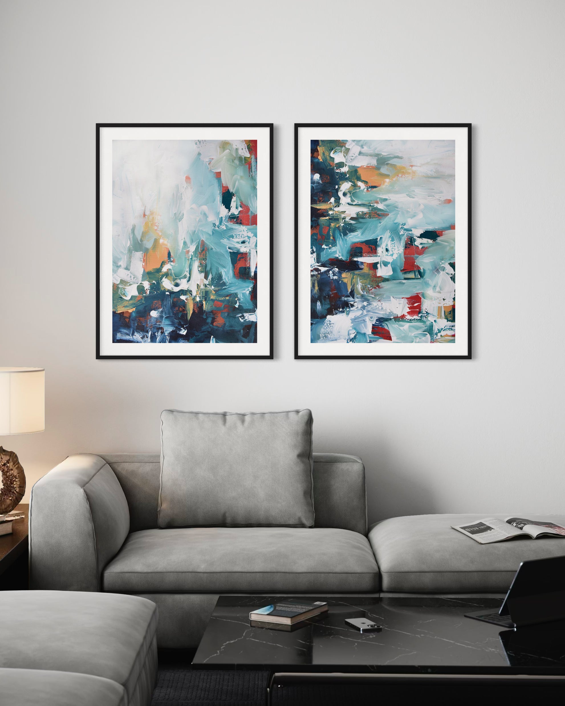 Two abstract paintings on a wall above a gray sofa in a living room.