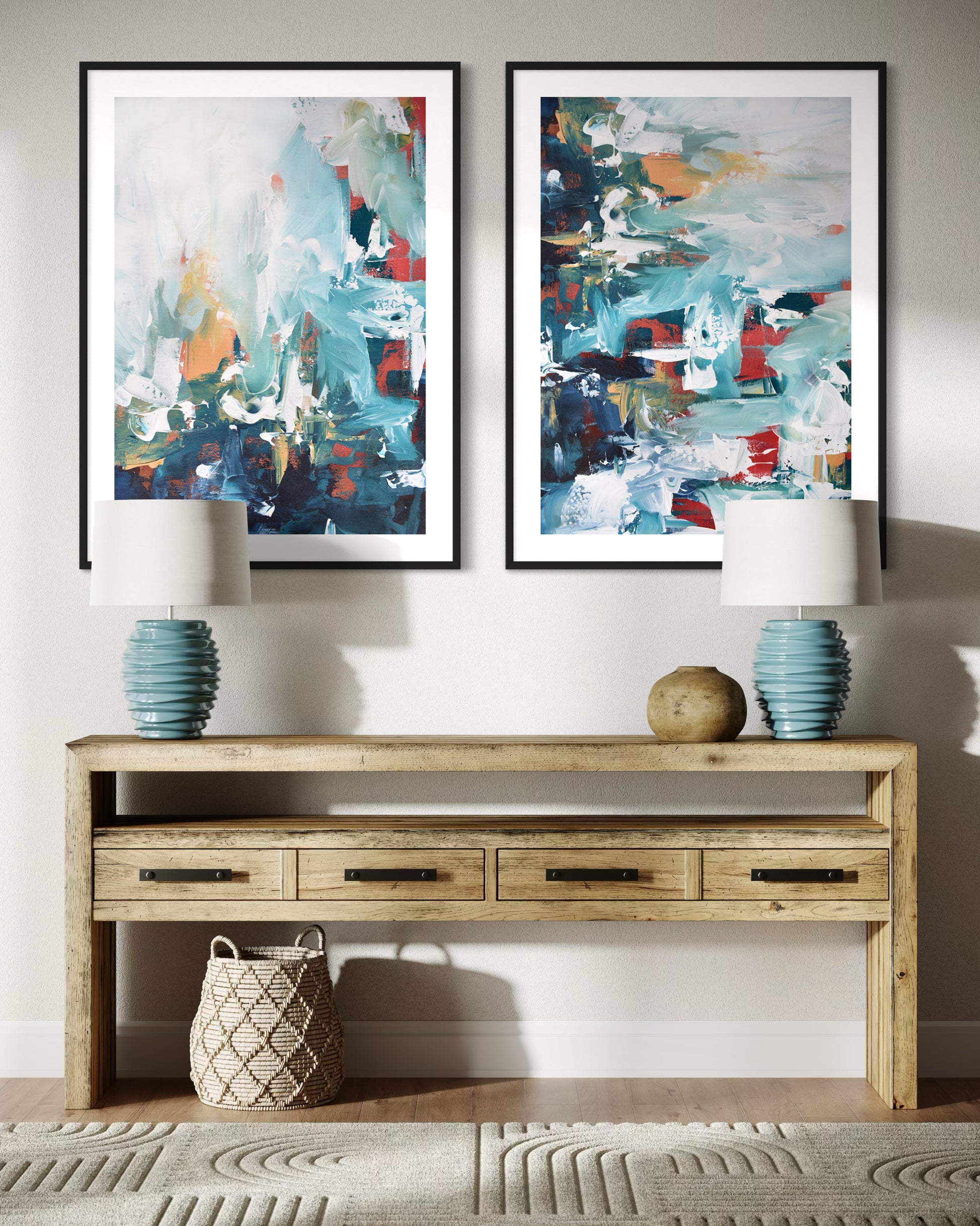 Two abstract paintings on a wall above a wooden console table with decorative items.