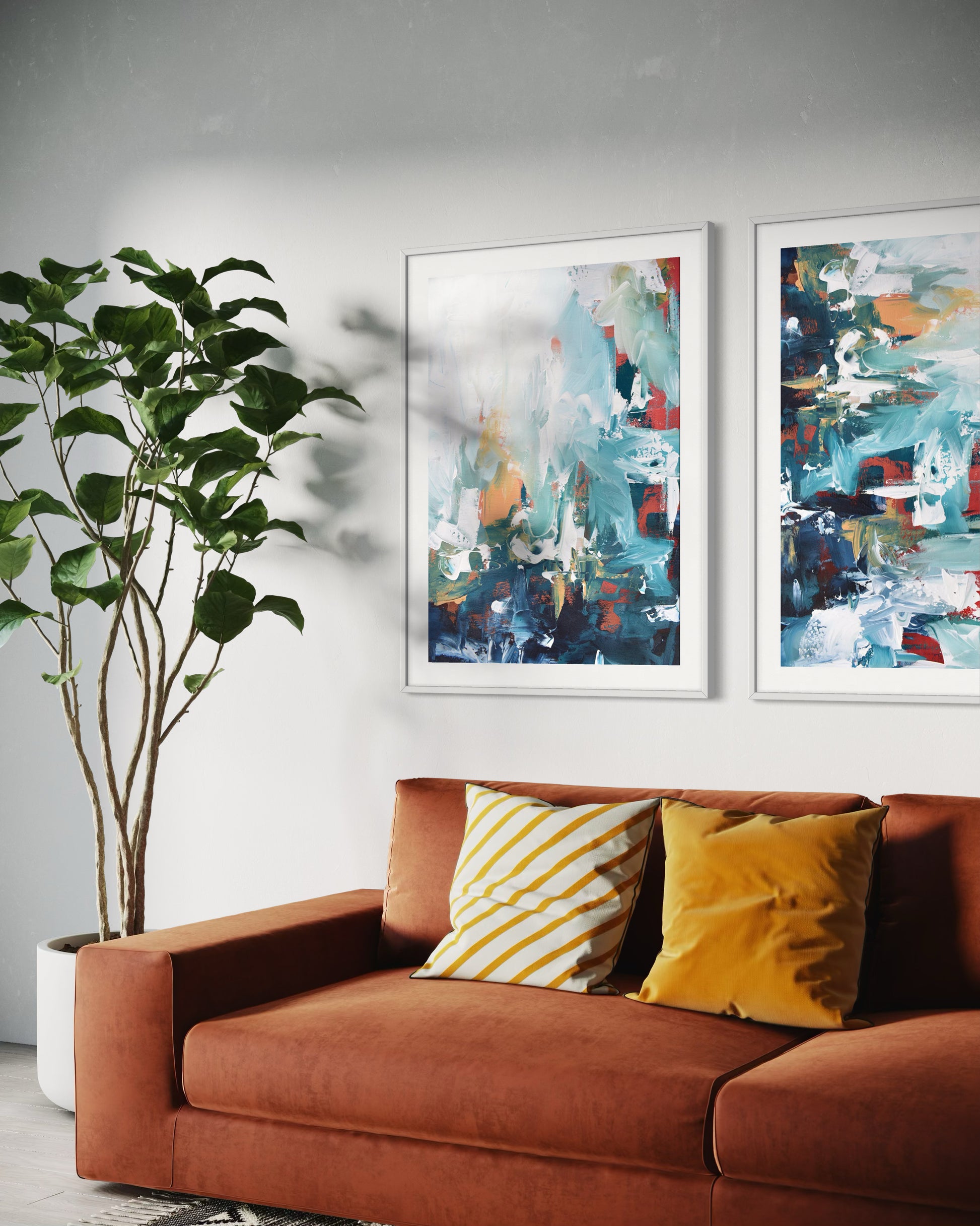 Brown sofa with yellow and white striped pillows, two abstract paintings on the wall, and a potted plant.