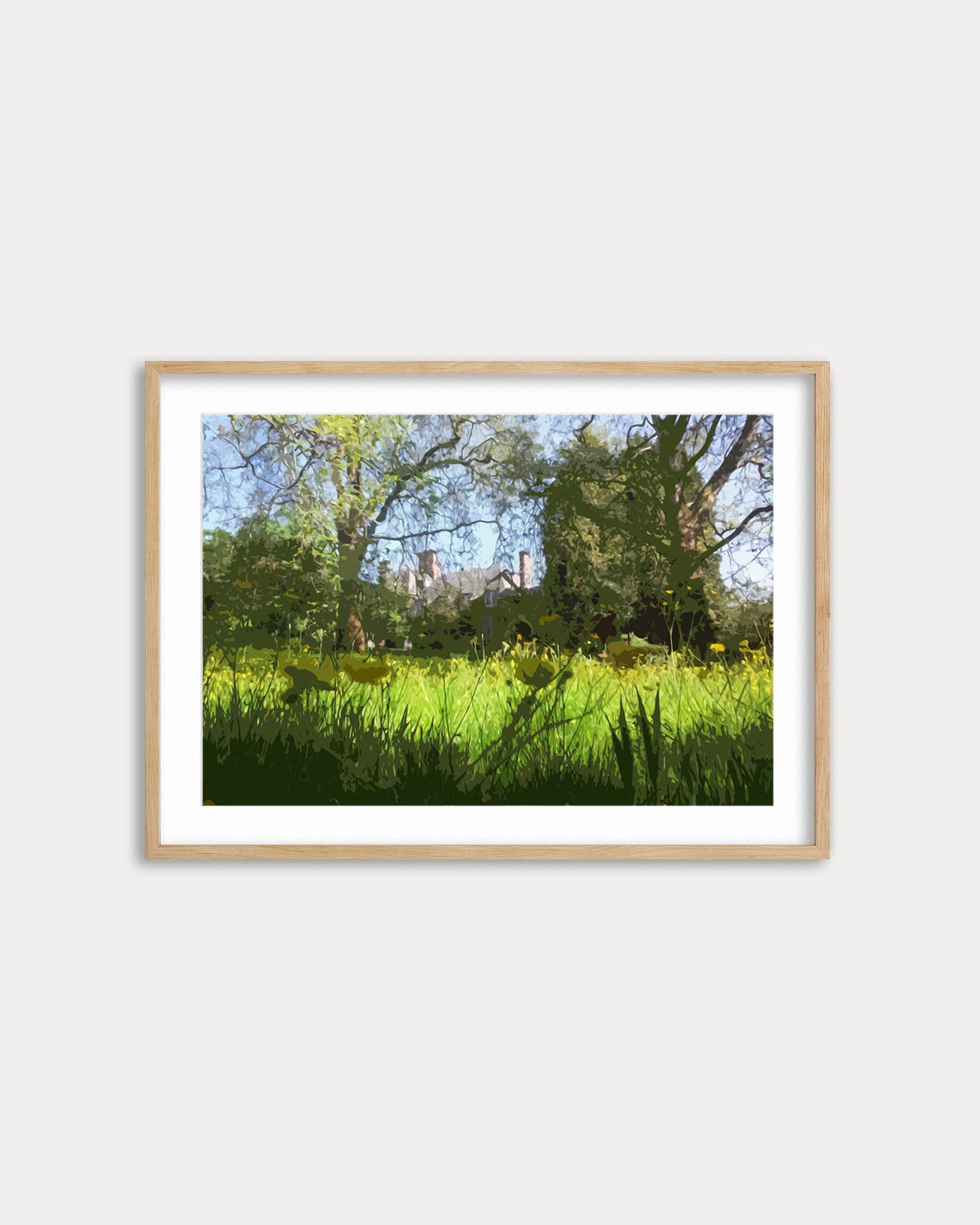 Framed photograph of a lush green field with trees on a white wall