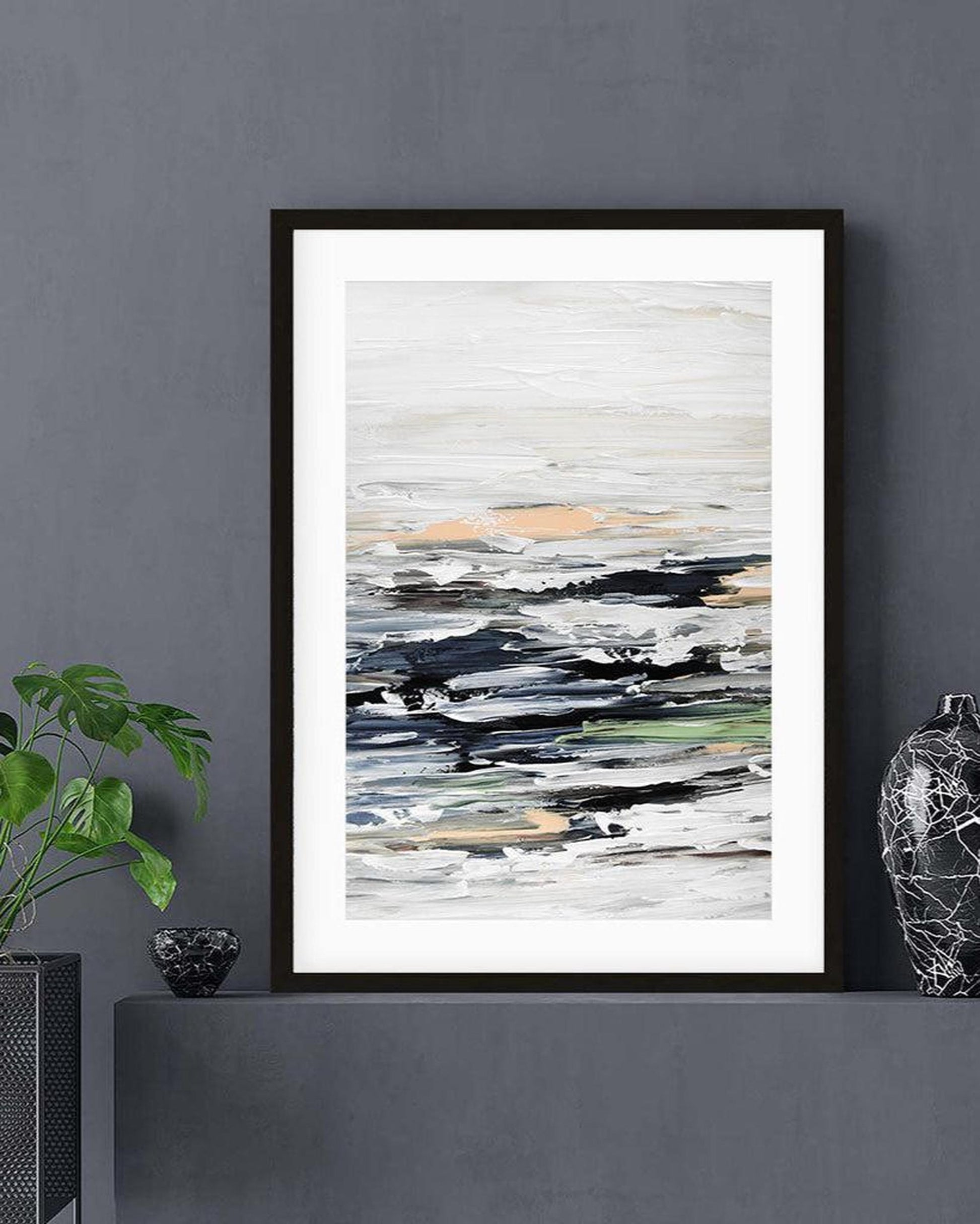 Framed abstract art print on a gray wall with decorative items.