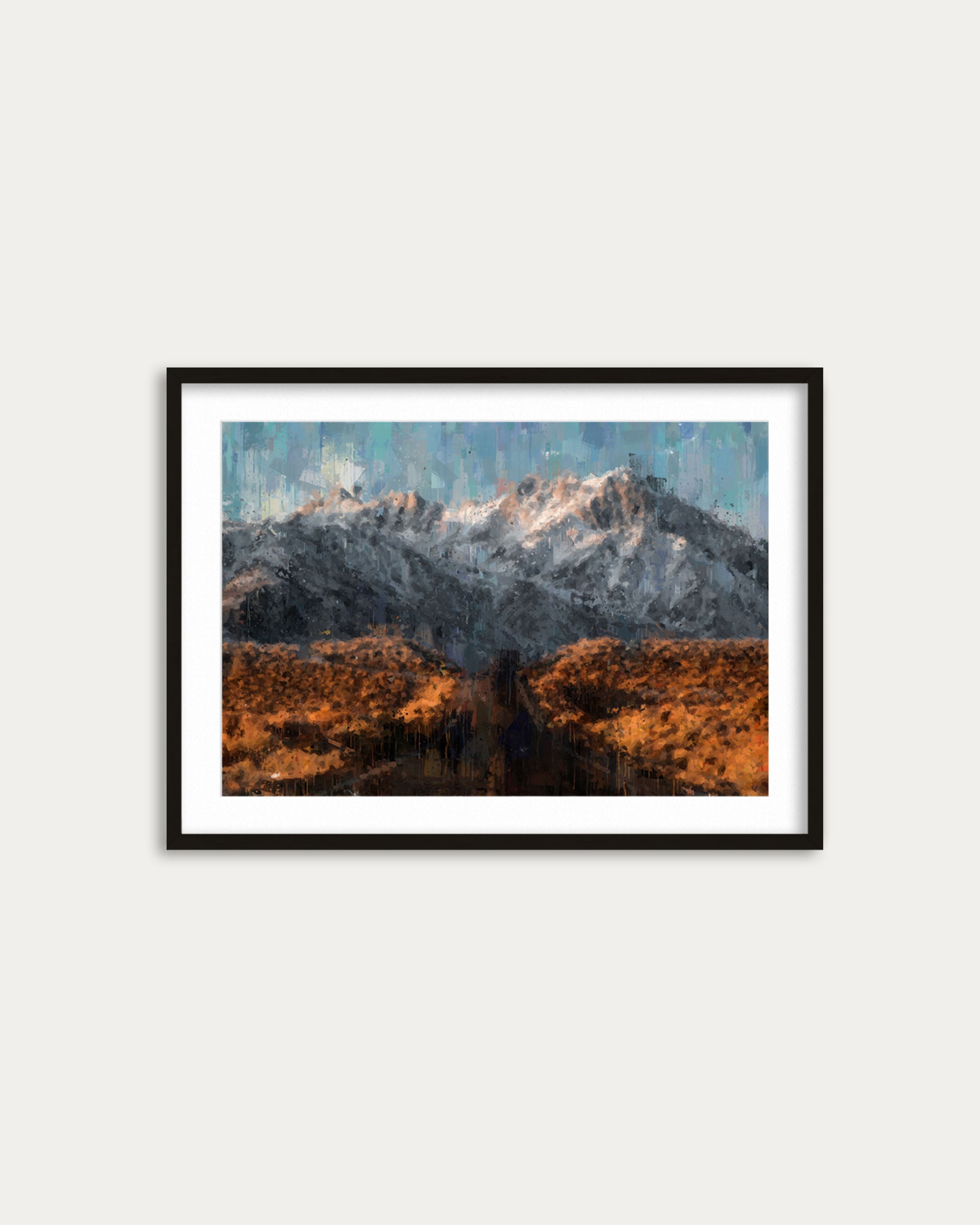 Framed artwork of a mountain landscape with snow-capped peaks on a white wall.