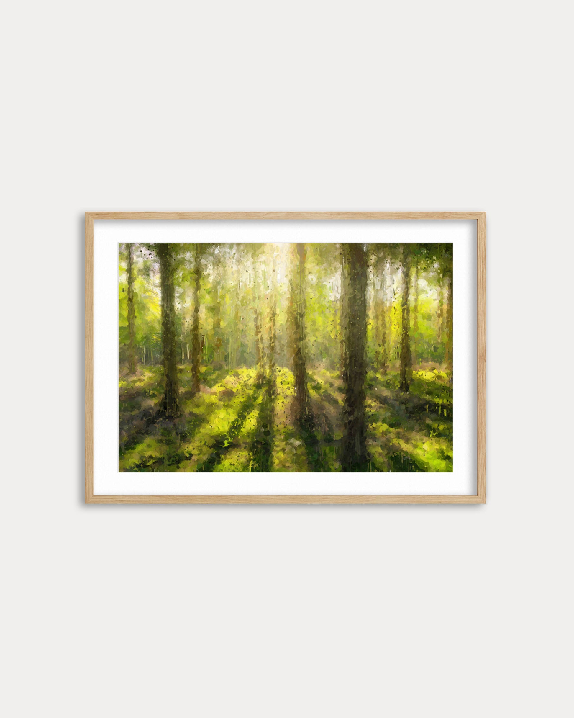 Framed artwork of a forest scene with sunlight filtering through the trees on a white wall.