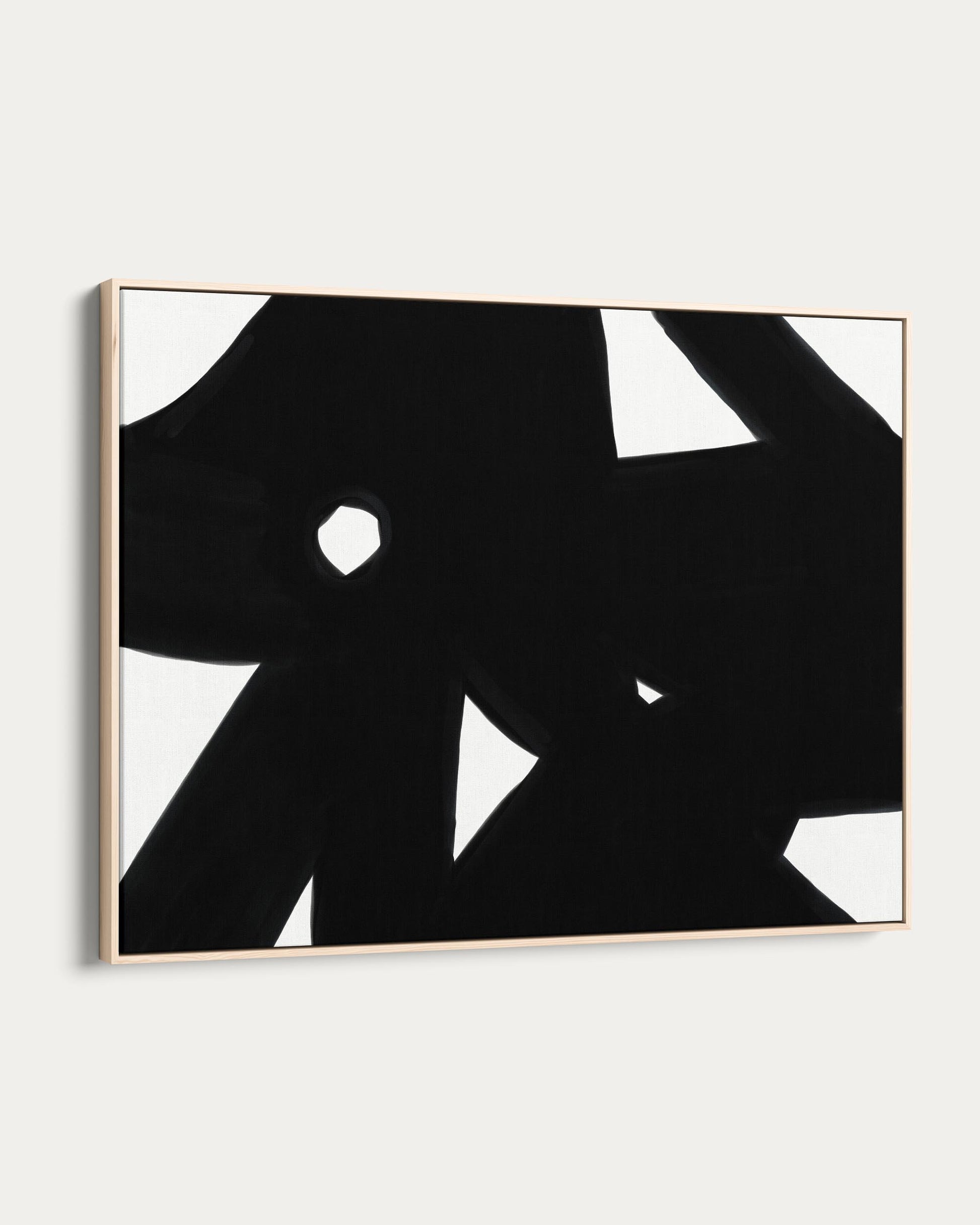 Abstract black and white artwork in a gold frame on a white wall