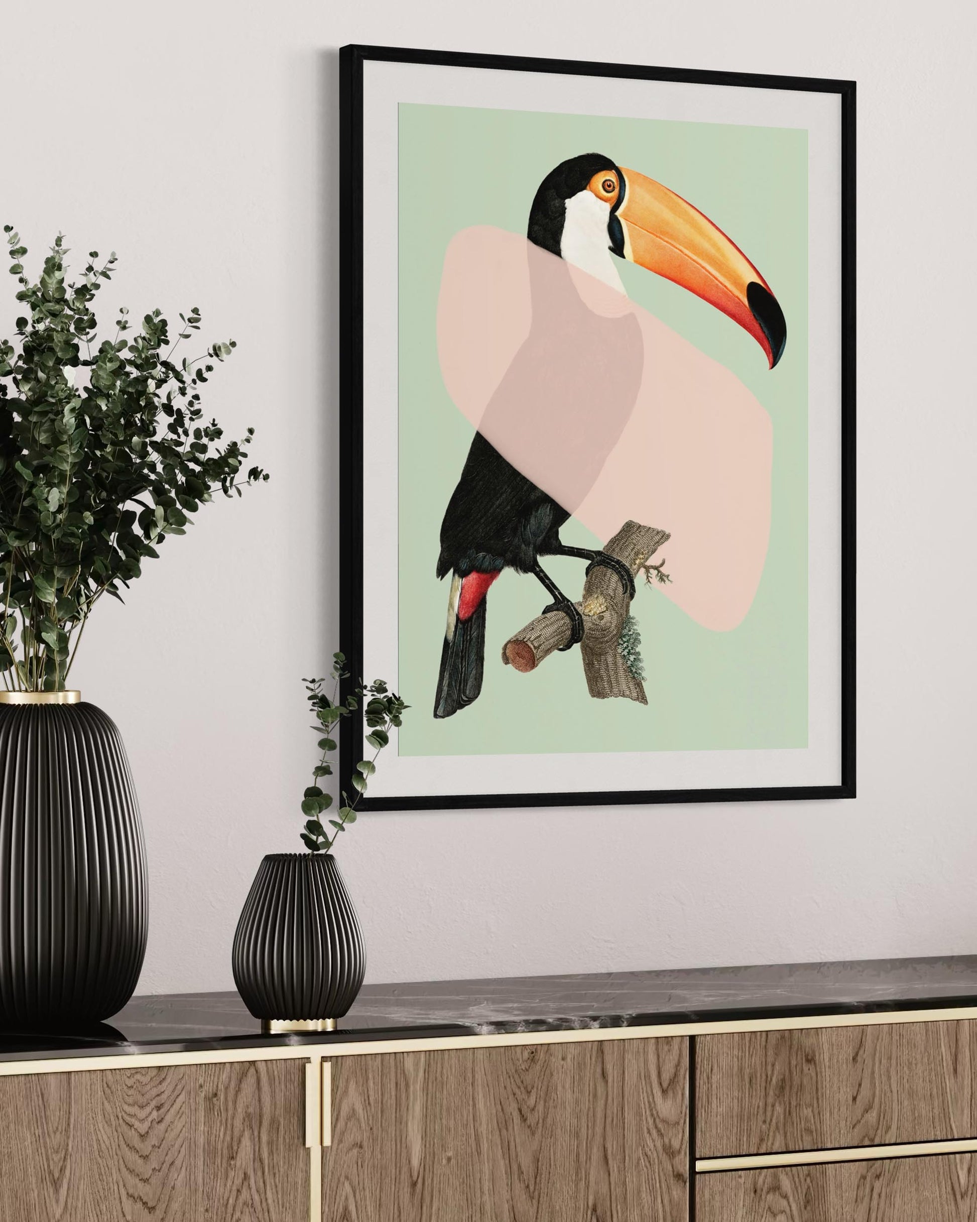 Framed artwork of a toucan on a wall above a wooden cabinet with decorative vases.