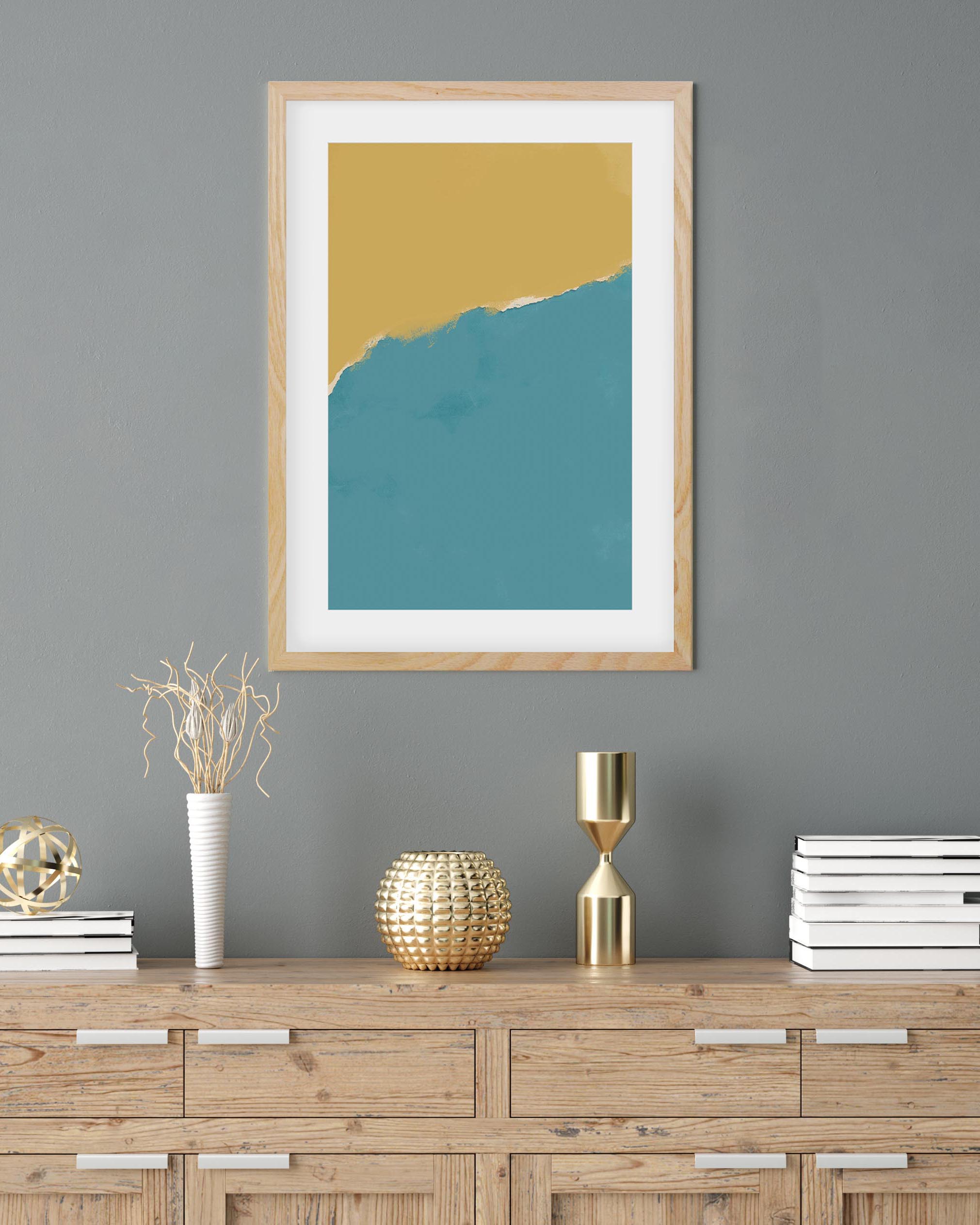 Framed abstract art piece with yellow and blue gradient on a gray wall above a wooden console table.