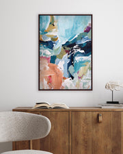 Abstract painting on a wall above a wooden cabinet with an open book and decorative items.