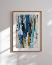 Framed abstract art print with blue, white, and gold colors on a light gray wall.