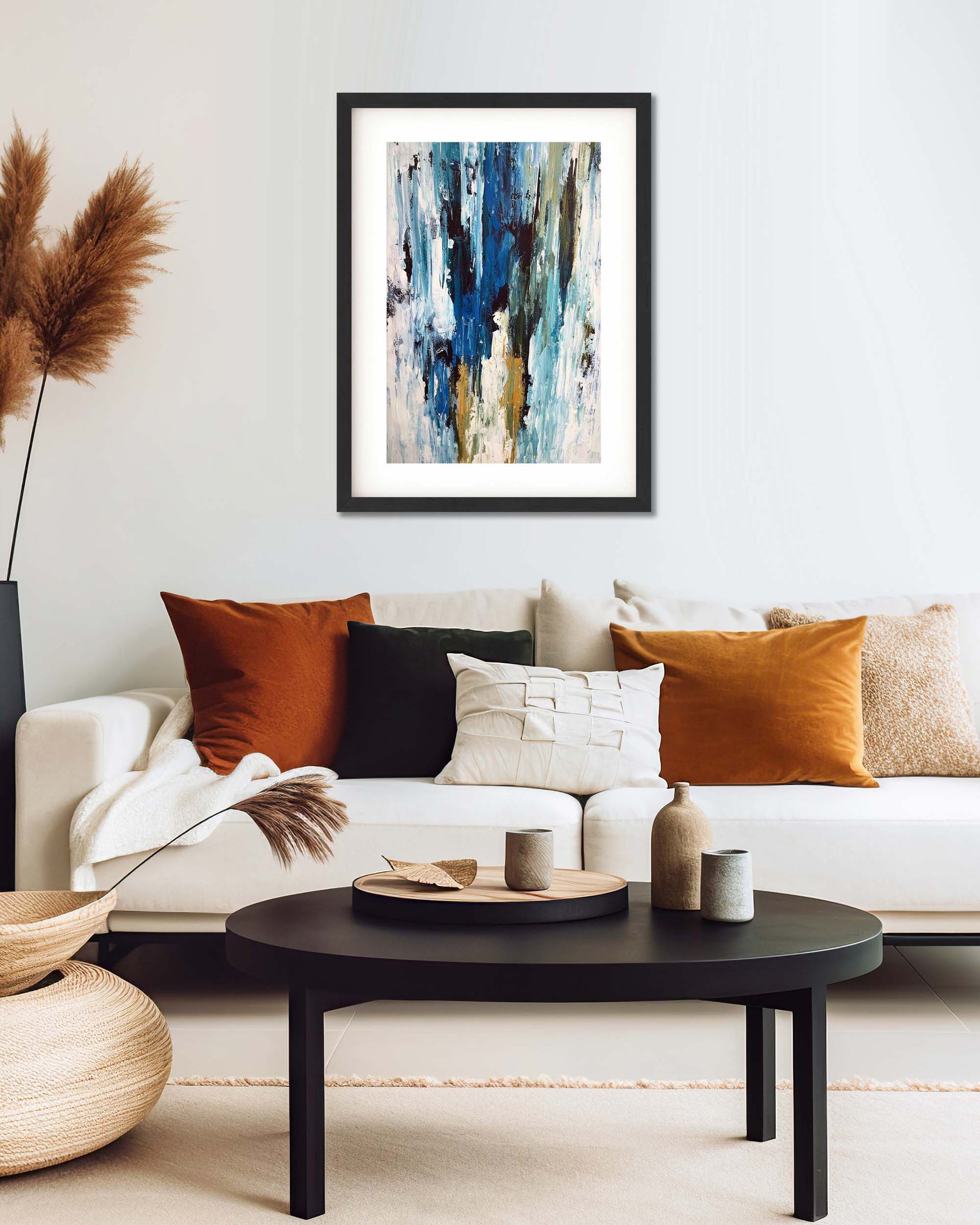 modern blue abstract wall art painting print framed in black frame, above cream sofa with autumn orange scatter cushions in modern living room 