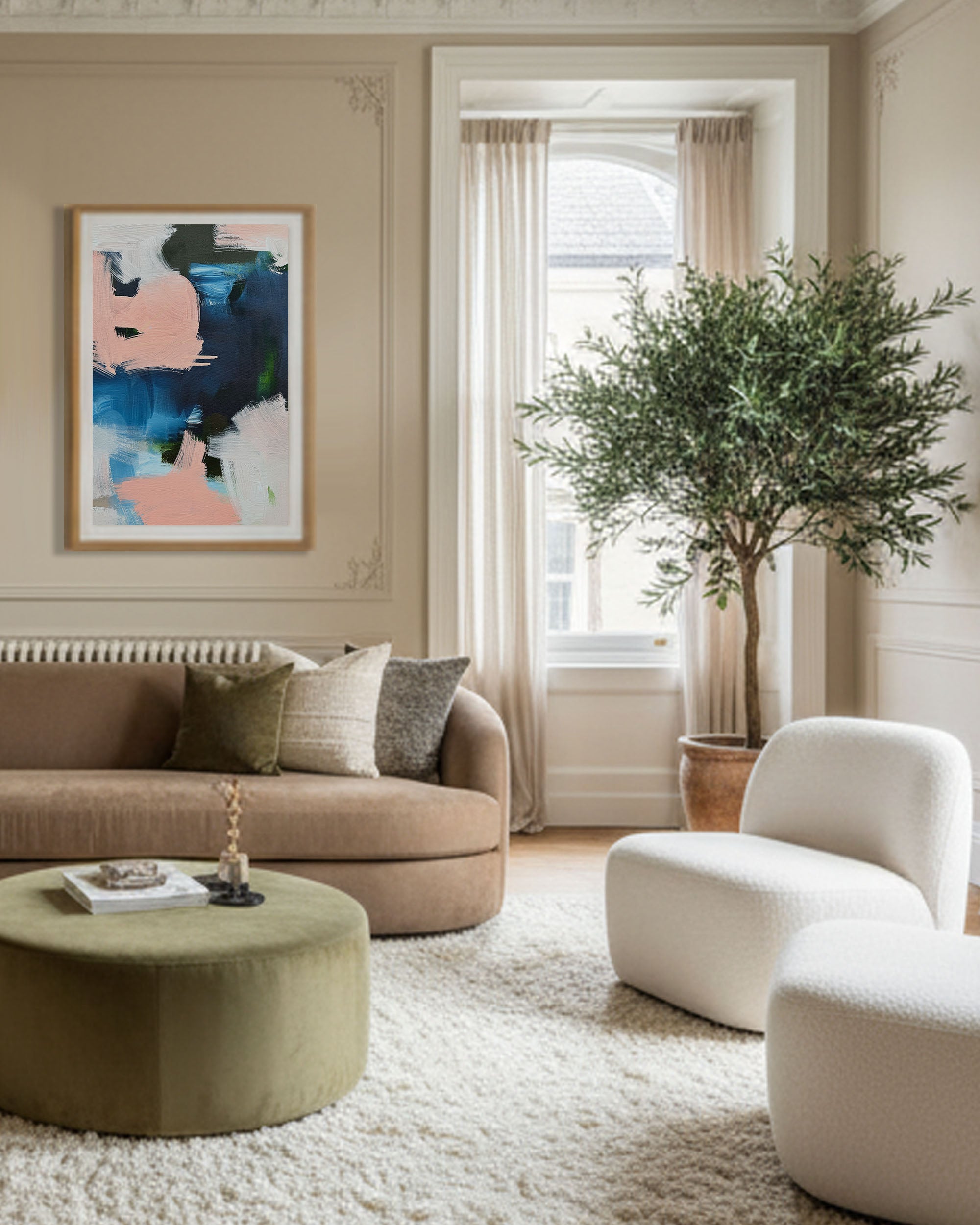 Modern living room with beige sofa, round ottoman, and abstract art on wall.