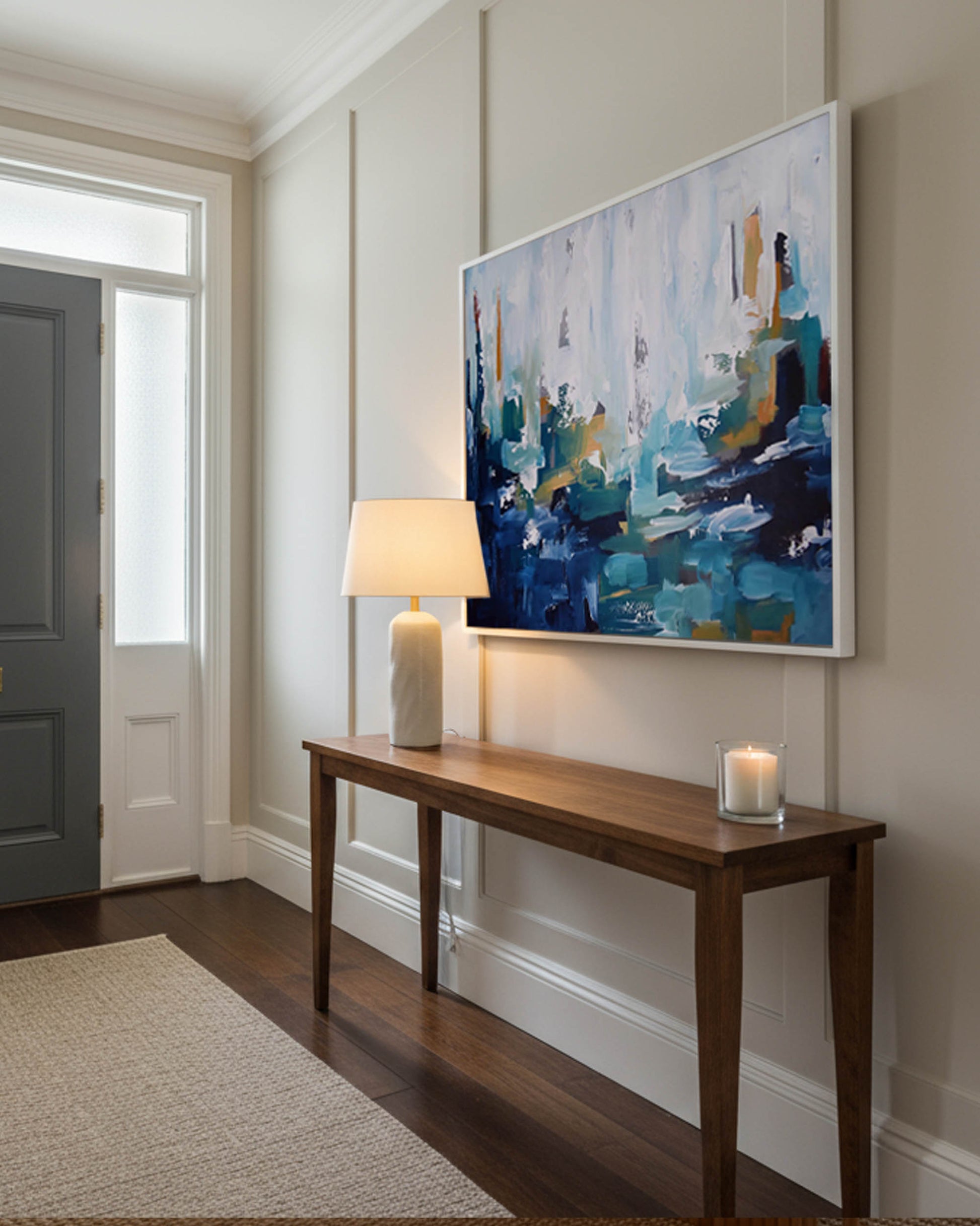 Modern interior with a wooden console table, lamp, and abstract painting on a wall.