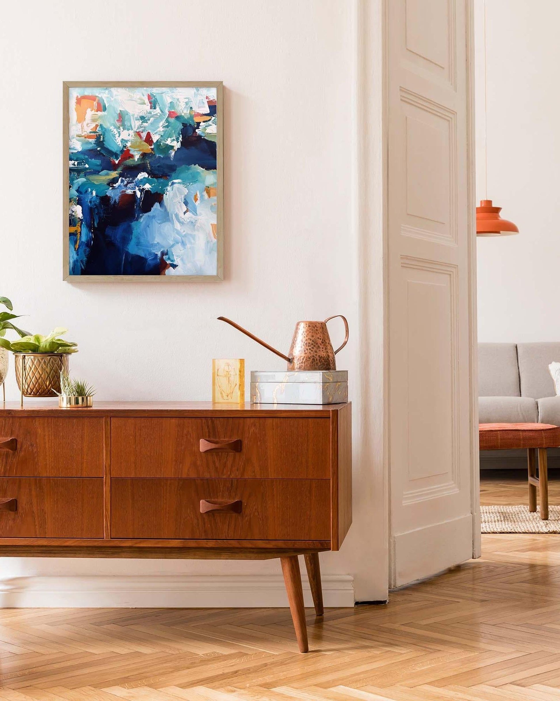 Wooden sideboard with abstract painting above it in a living room setting