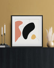 Framed abstract art piece on a wall with decorative items.