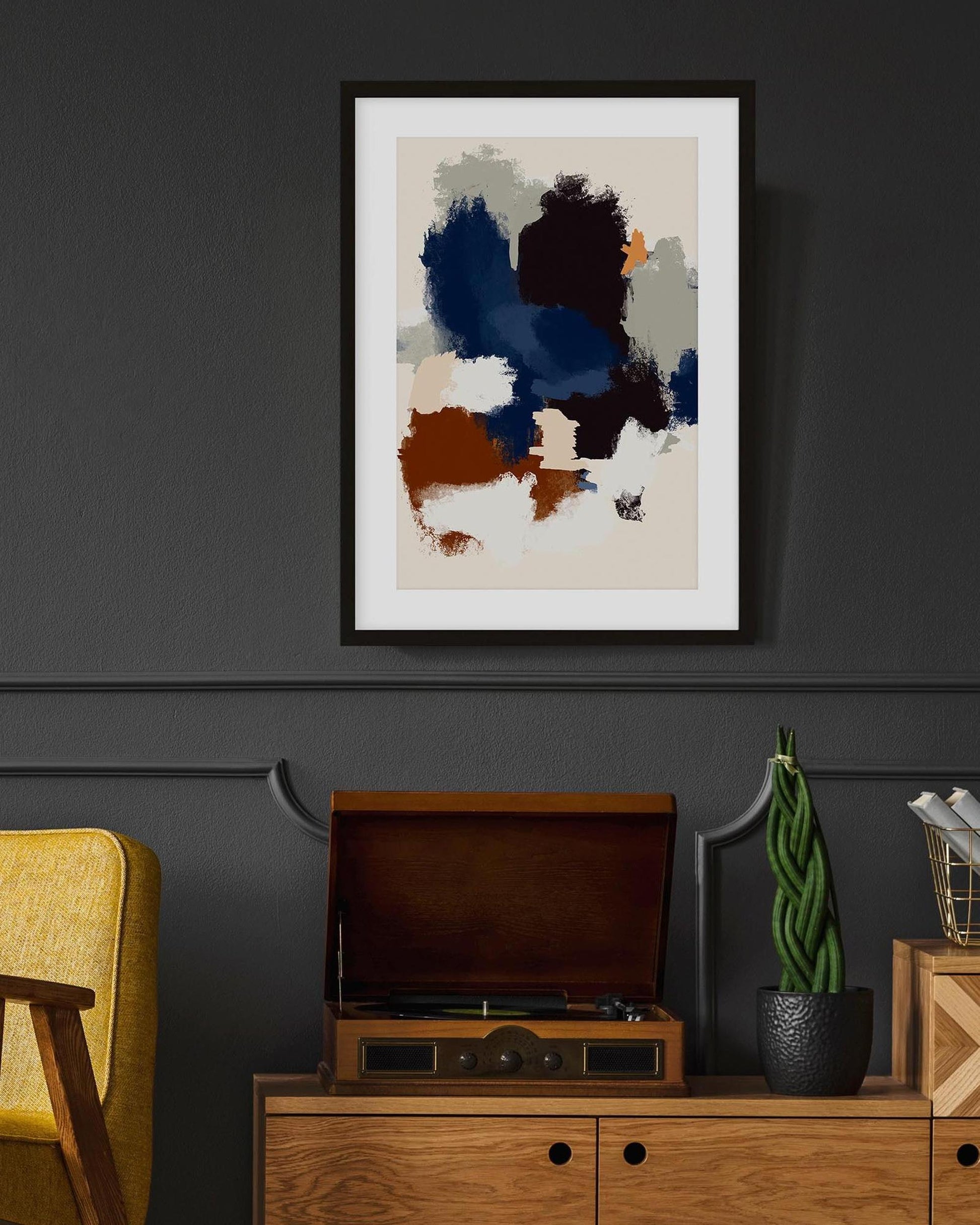 Abstract art print on a wall above a wooden cabinet with a yellow chair and decorative items.