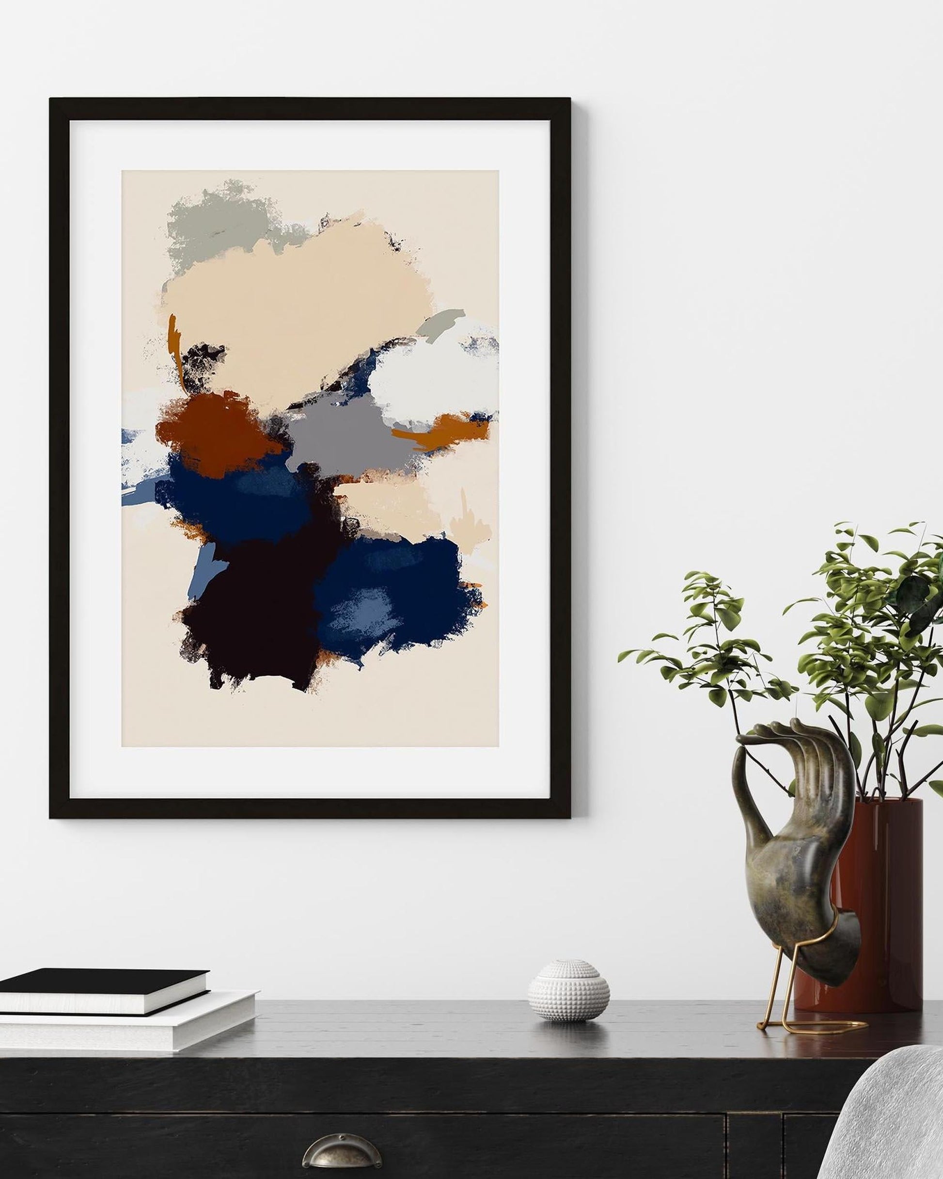 Abstract art print in a black frame on a wall above a desk with decor items.
