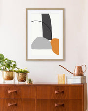 Abstract art print on a wall above a wooden cabinet with decorative items.