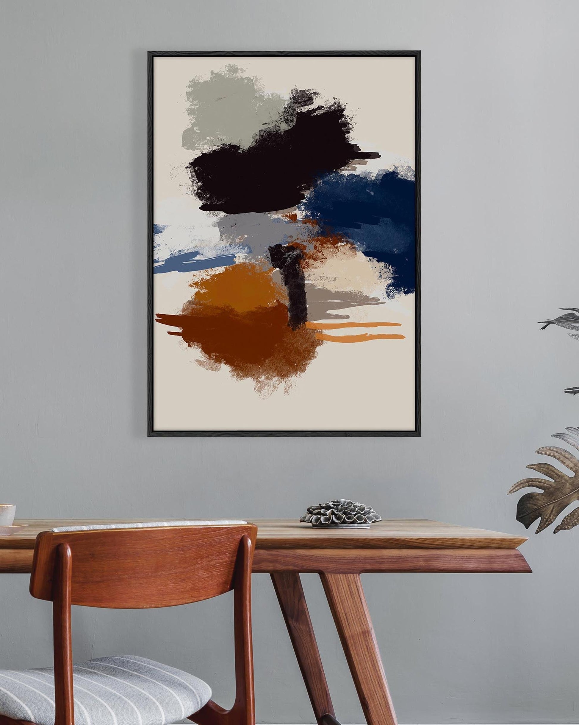 Abstract art print on a wall above a wooden table with a chair.