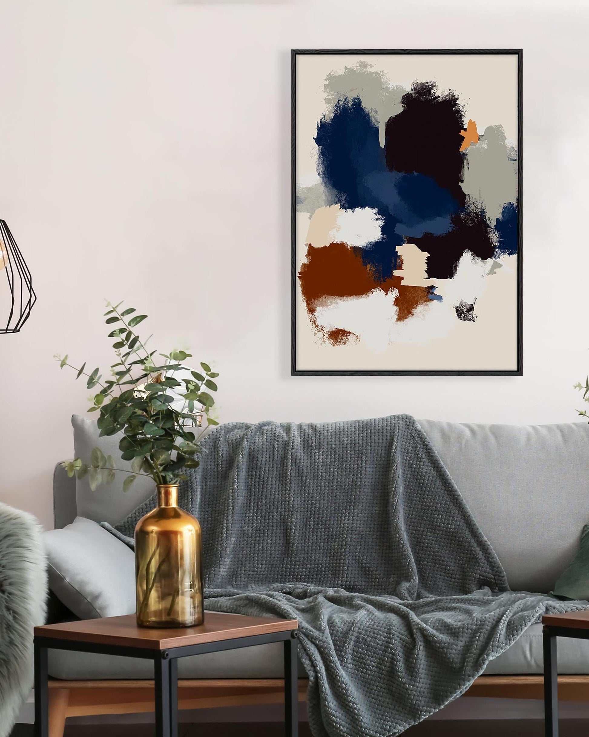 Living room with a gray sofa, abstract art on the wall, and a gold vase on a side table.