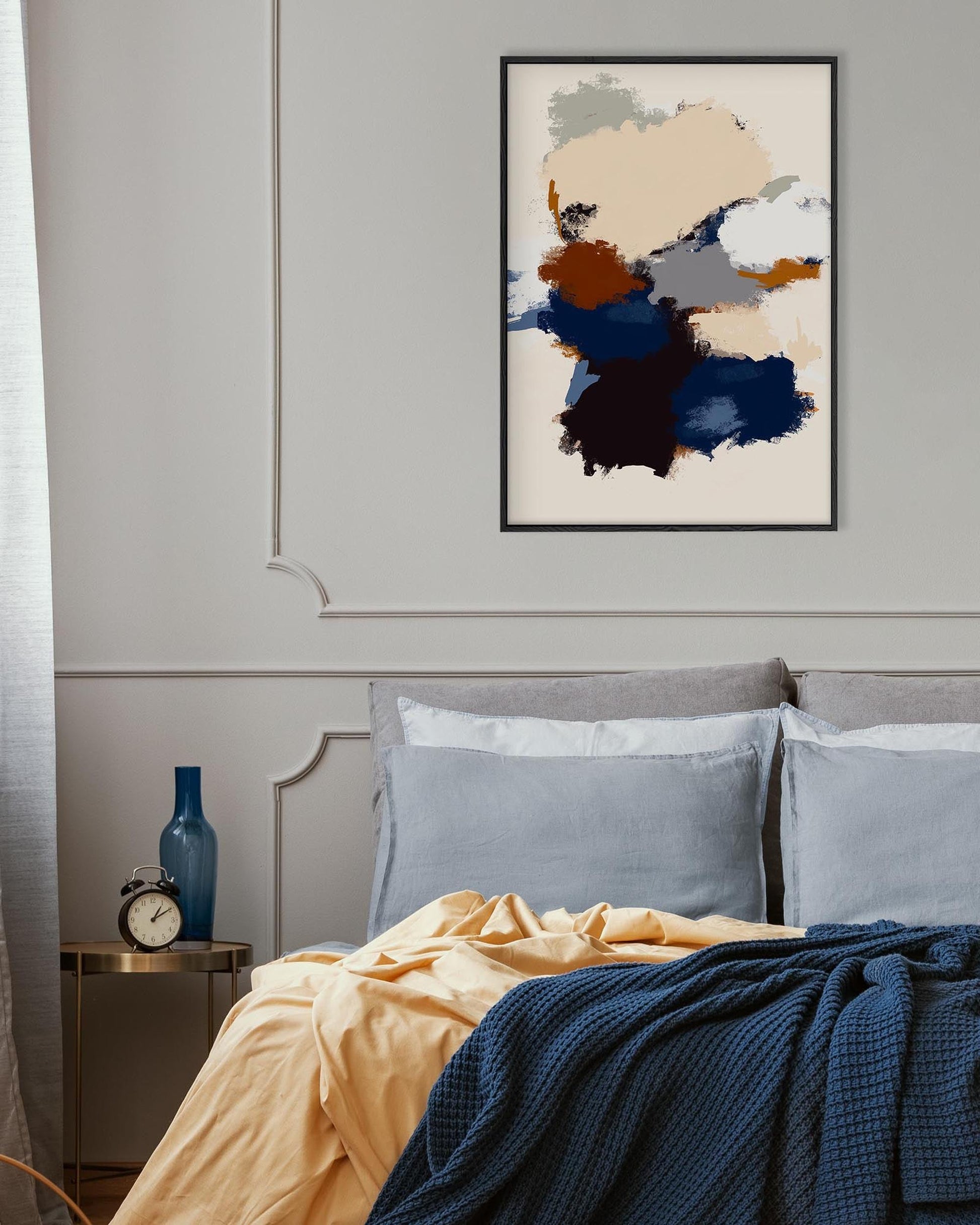 Modern bedroom with abstract art on the wall, bed with blue and yellow bedding, and nightstand with clock.