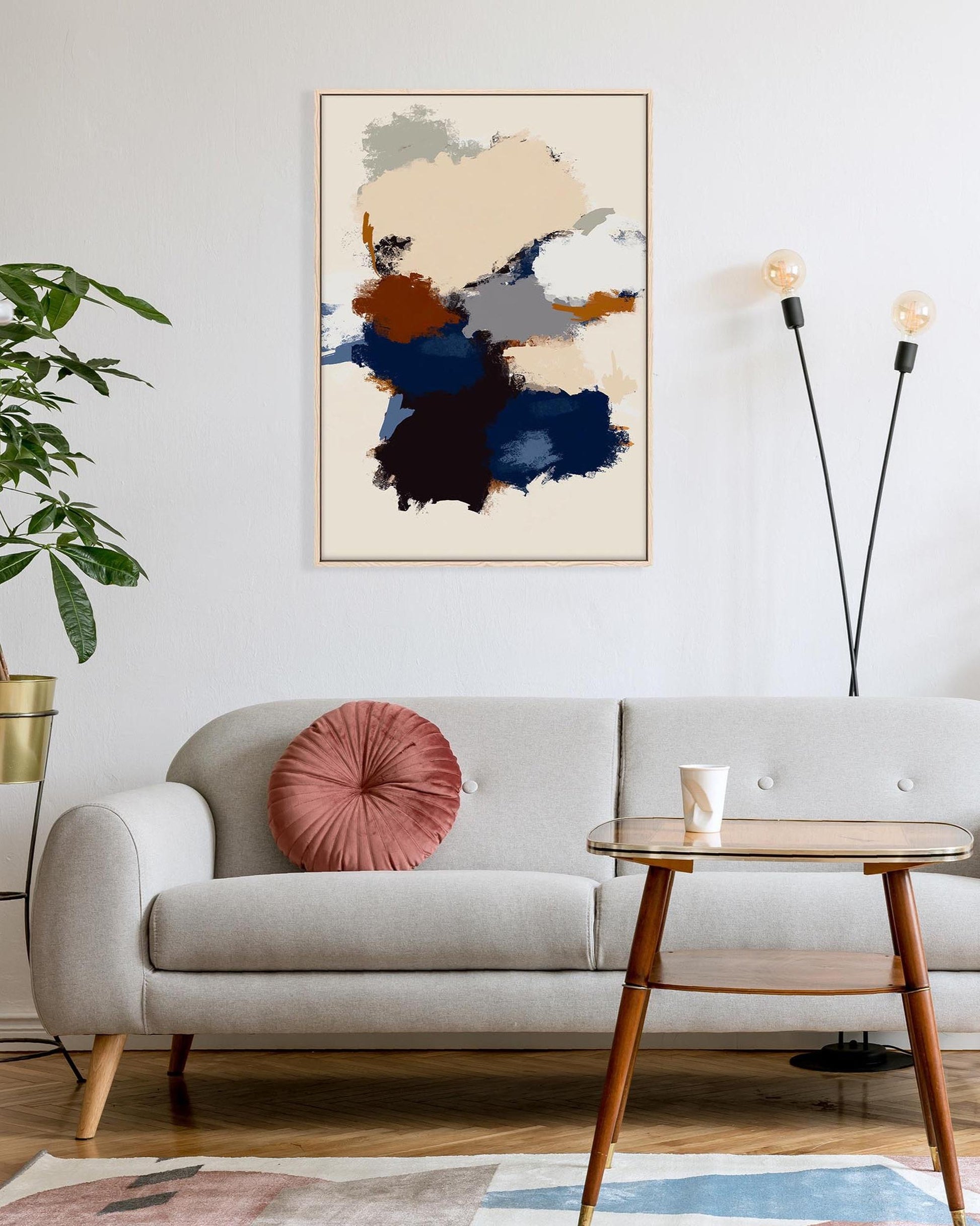 Modern living room with a gray sofa, abstract art, and a lamp.