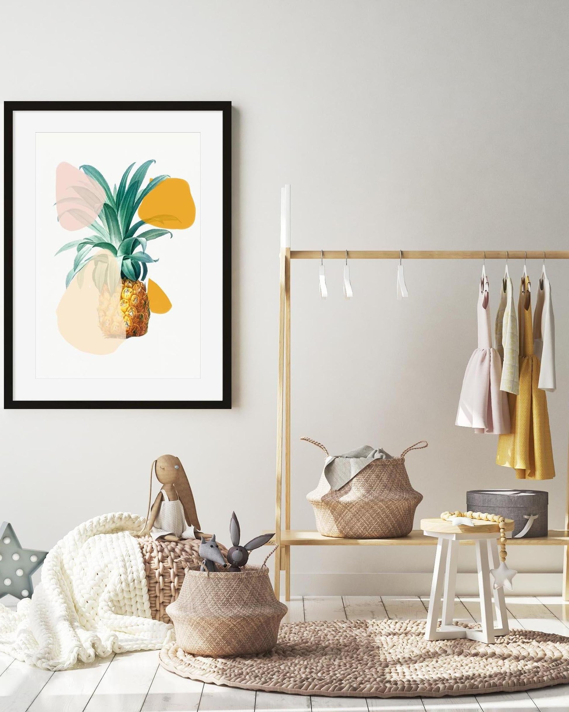 Modern interior with a framed pineapple art print, clothing rack, and decorative items.