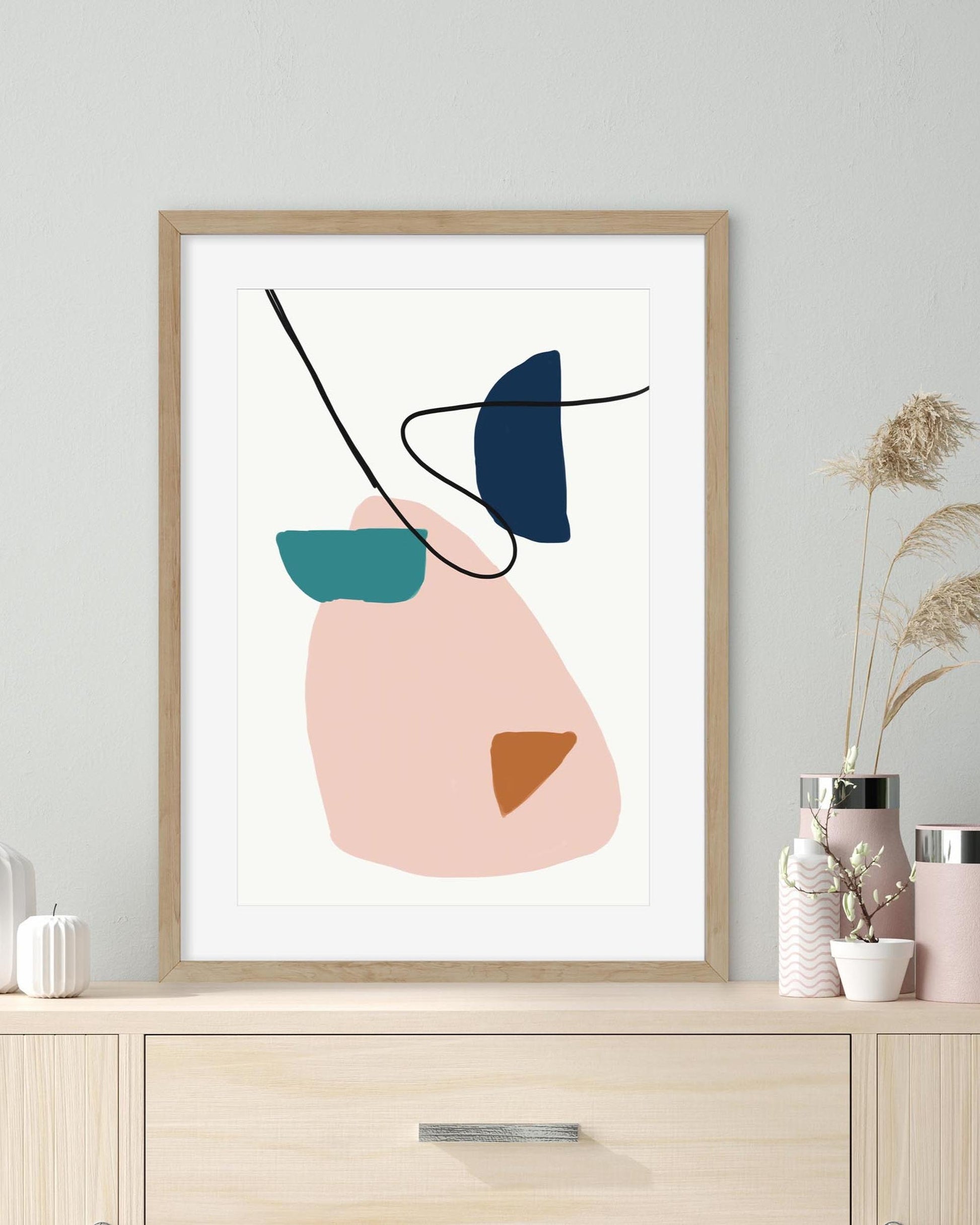 Framed abstract art print on a wall with decorative vases below.