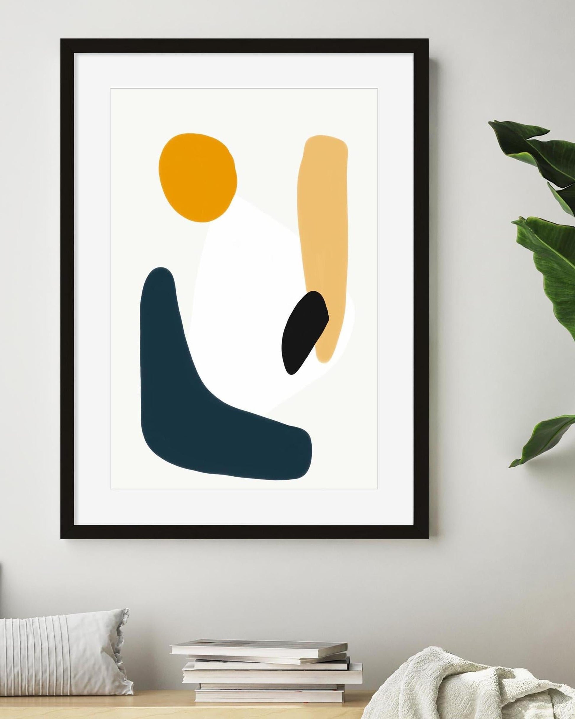 Framed abstract art print with geometric shapes on a white wall.