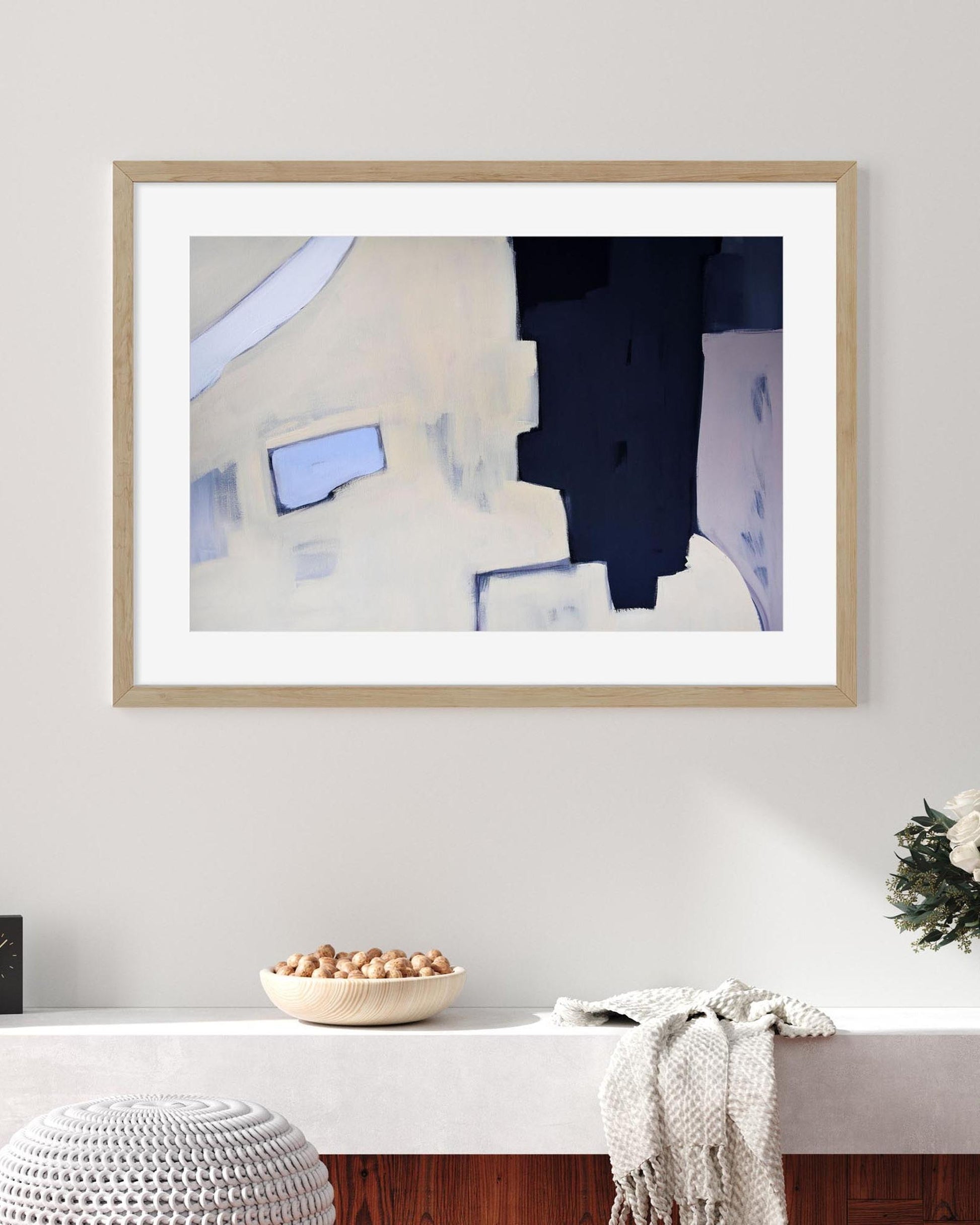 Framed abstract art piece on a wall above a white console table.