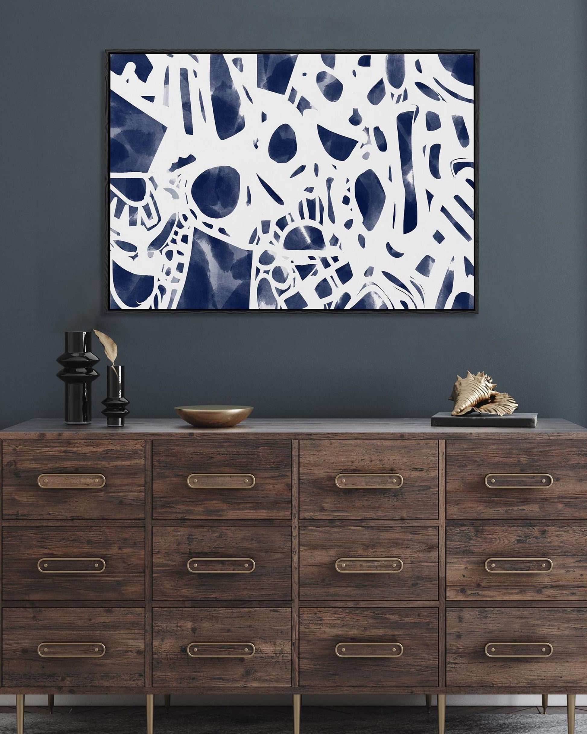 Wooden dresser with decorative items and abstract art on a gray wall